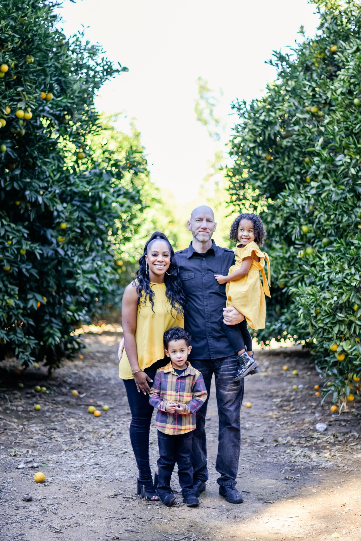 Family portrait in citrus grove with coordinated yellow and navy outfits.