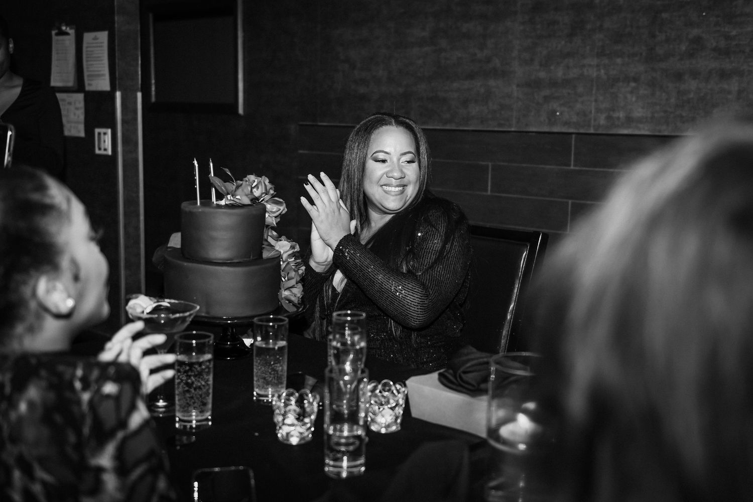 Person enjoying drinks with friends at a dimly lit bar table.