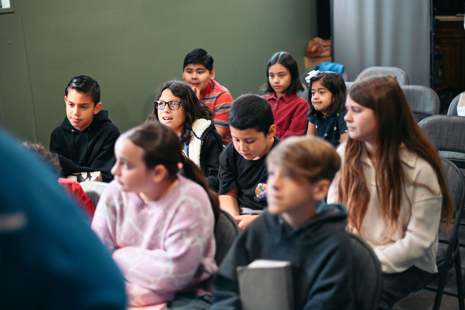 Young students sitting attentively in rows during a classroom or church gathering.