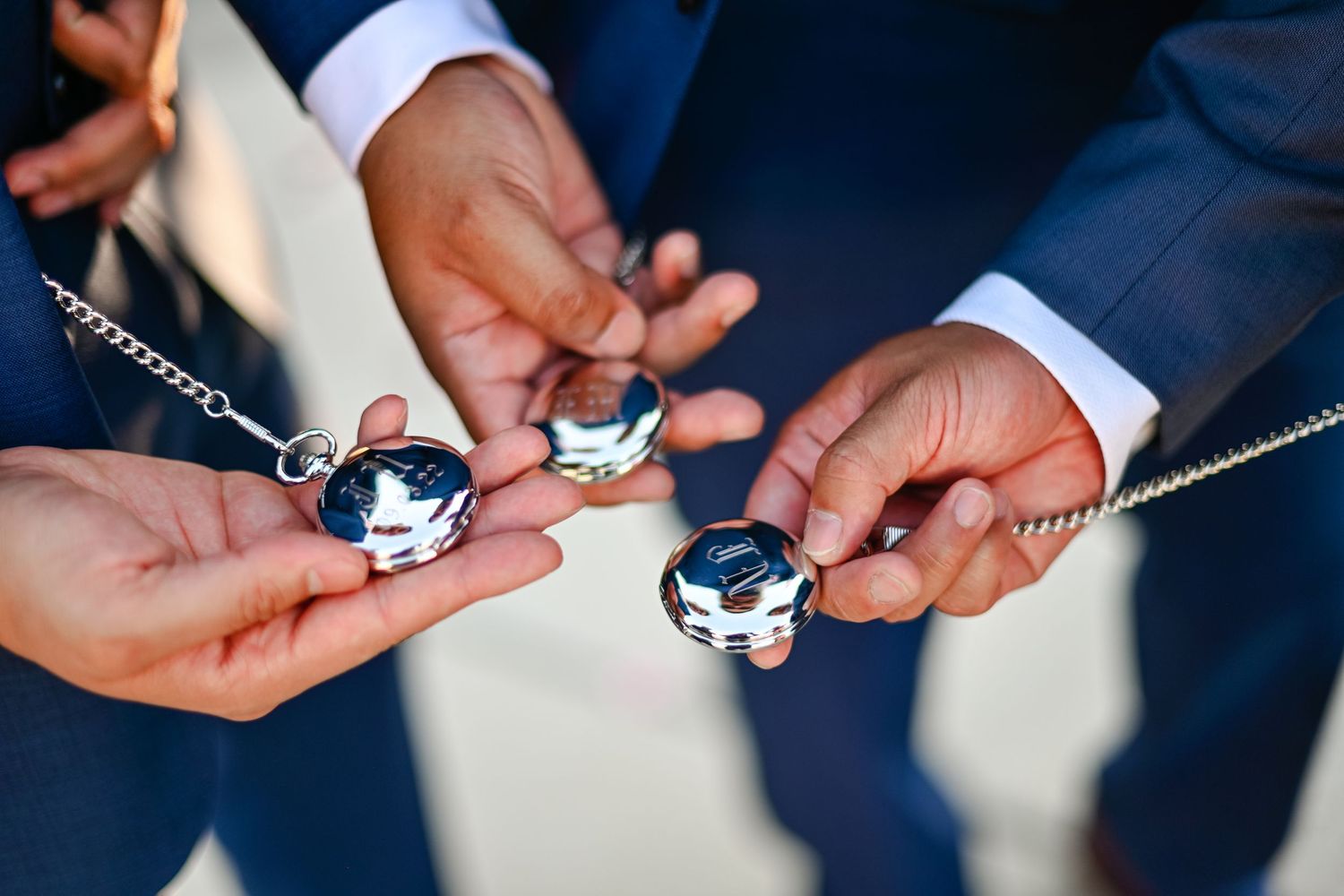 Close-up of hands holding pocket watches during wedding ceremony details.