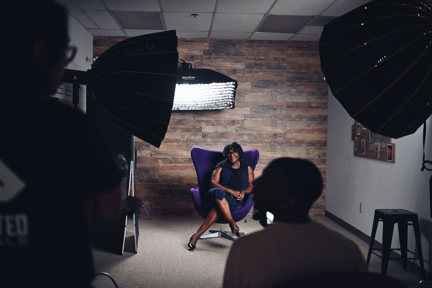 Behind-the-scenes photo shoot setup with lighting equipment and backdrop in a studio.