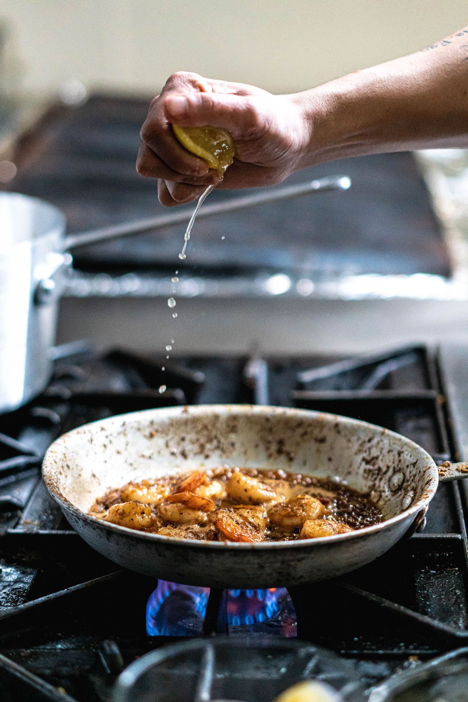 Chef squeezing lemon on to sizzling shrimp