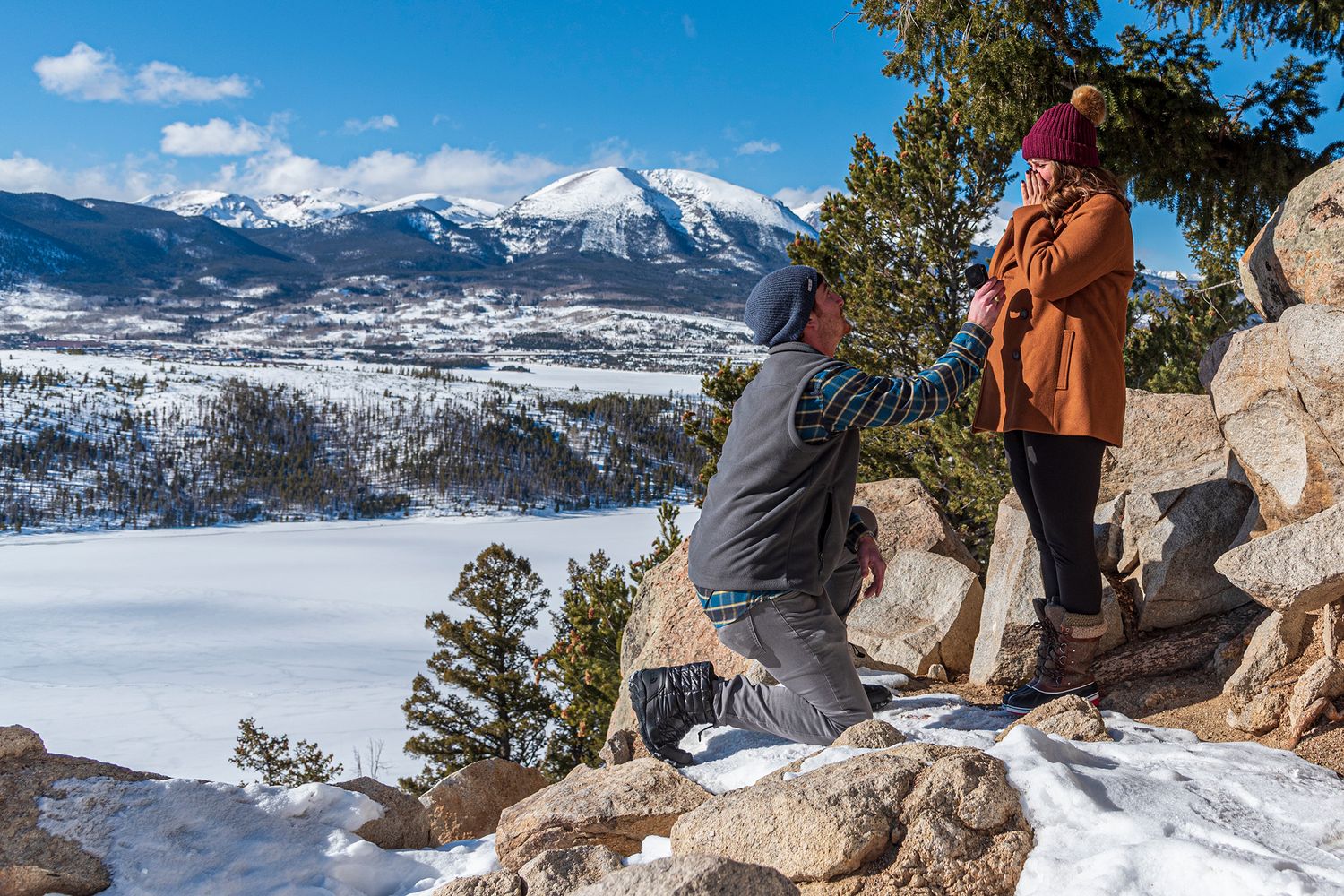 Man down on one knee asking his girlfriend to marry him at Sapphire Point Overlook in the winter.