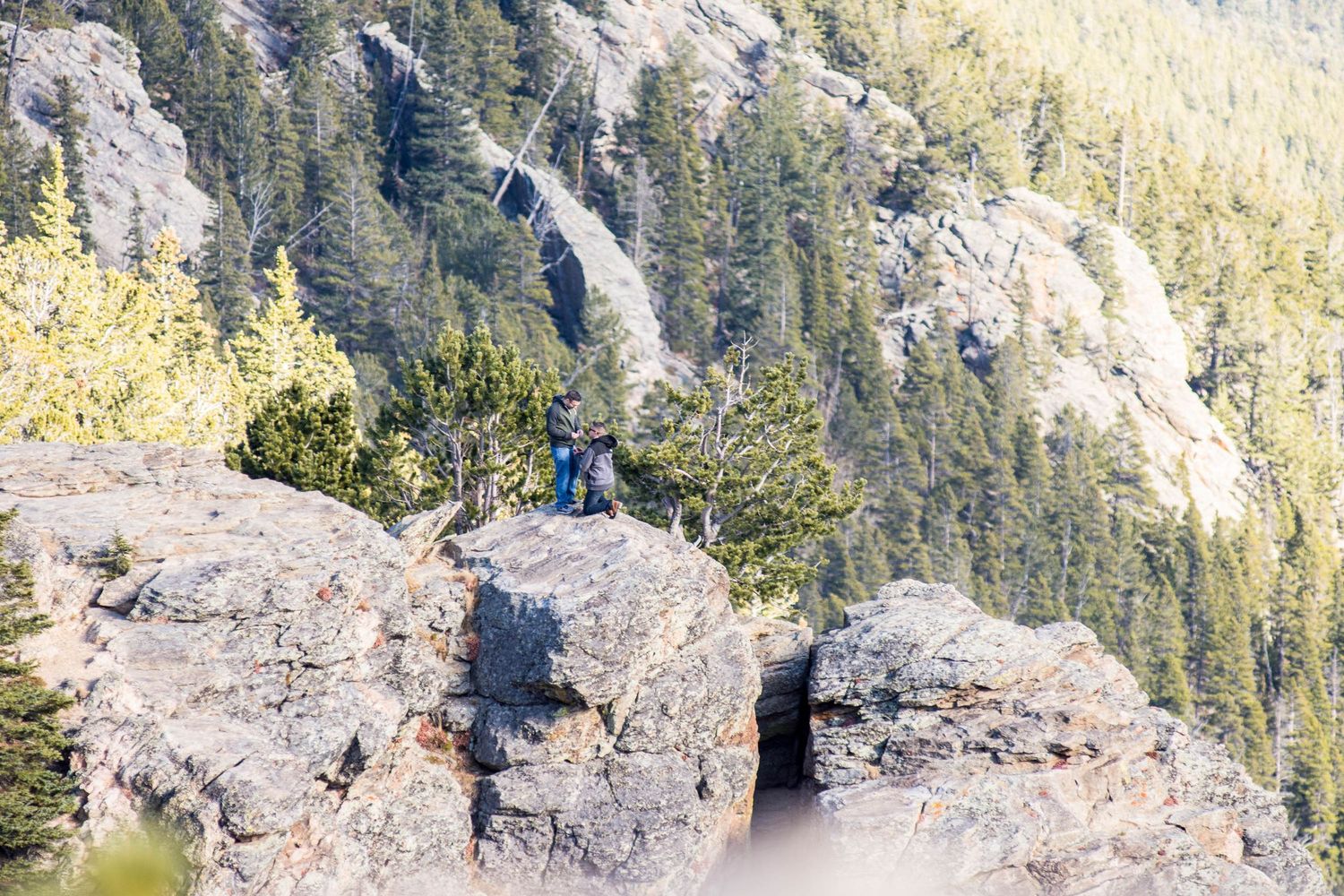 One man down on one knee proposing to his boyfriend on a cliff. Hidden photographer captured this surprise same sex marriage proposal.