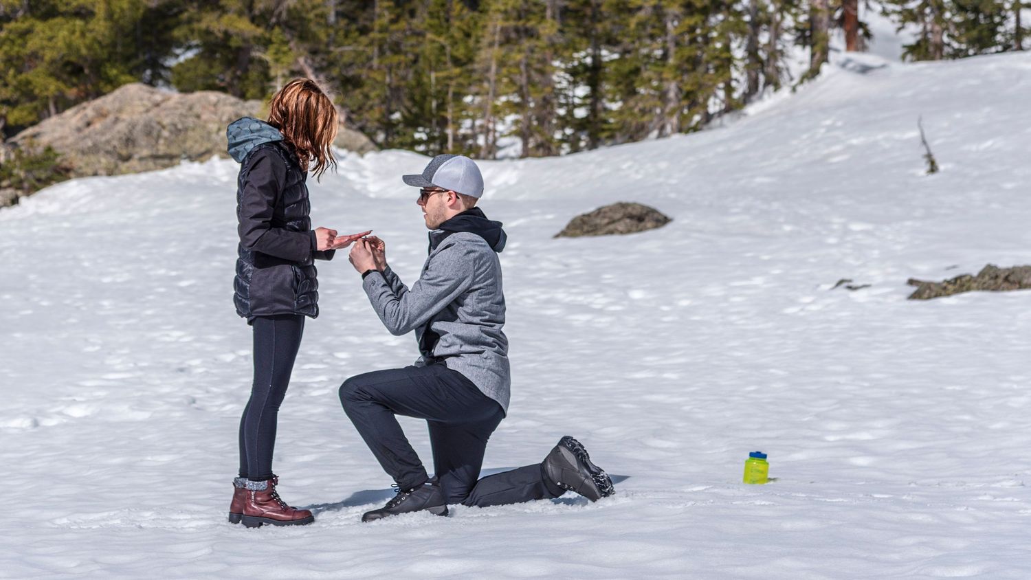 Man down placing ring on her at Dream Lake in Rocky Mountain National Park for a surprise marriage proposal captured by hidden photographer
