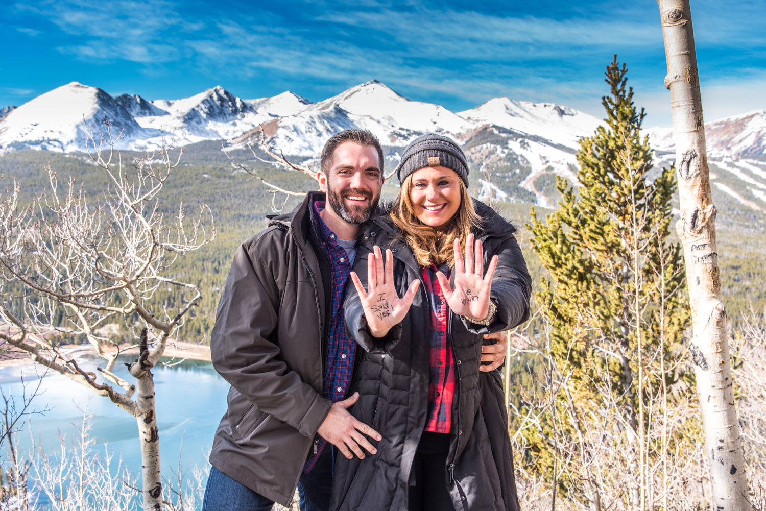Couple smiling after she said yes to his marriage proposal with the Ten Mile Range of Breckenridge, CO in the background.
