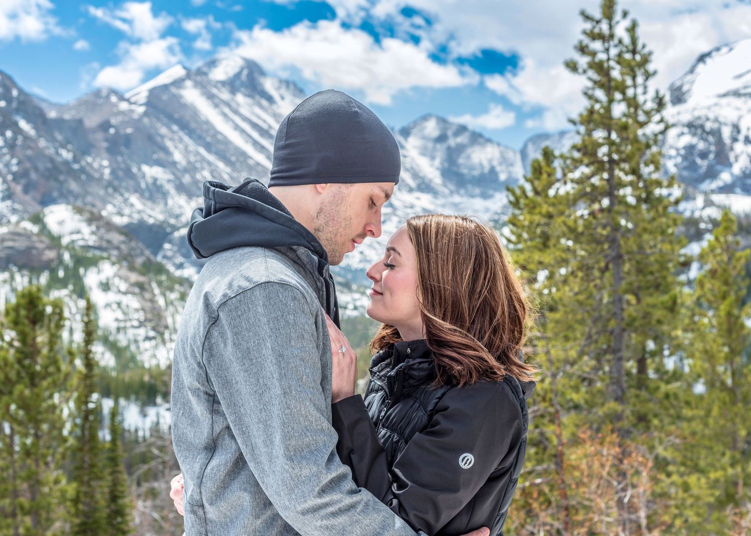 Couple embracing in RMNP Dream Lake after their surprise marriage proposal .