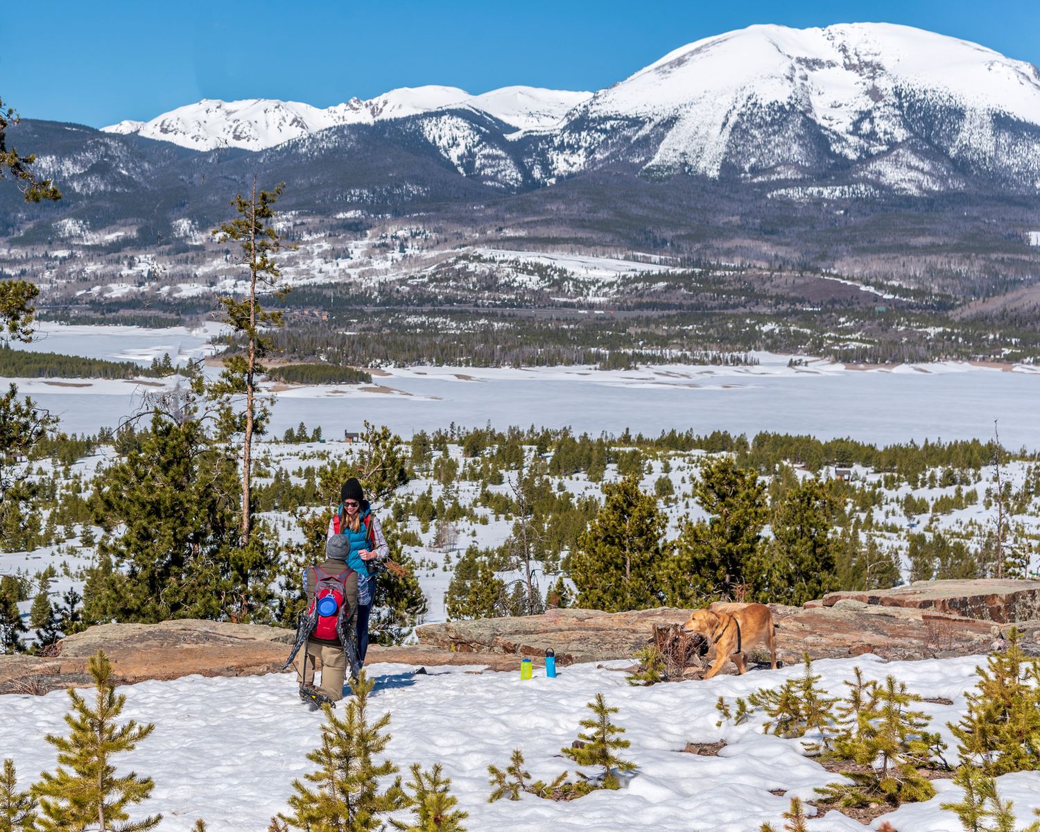 Snowy mountain marriage proposal near Breckenridge, CO where a hiker drops to one knee overlooking a frozen lake.