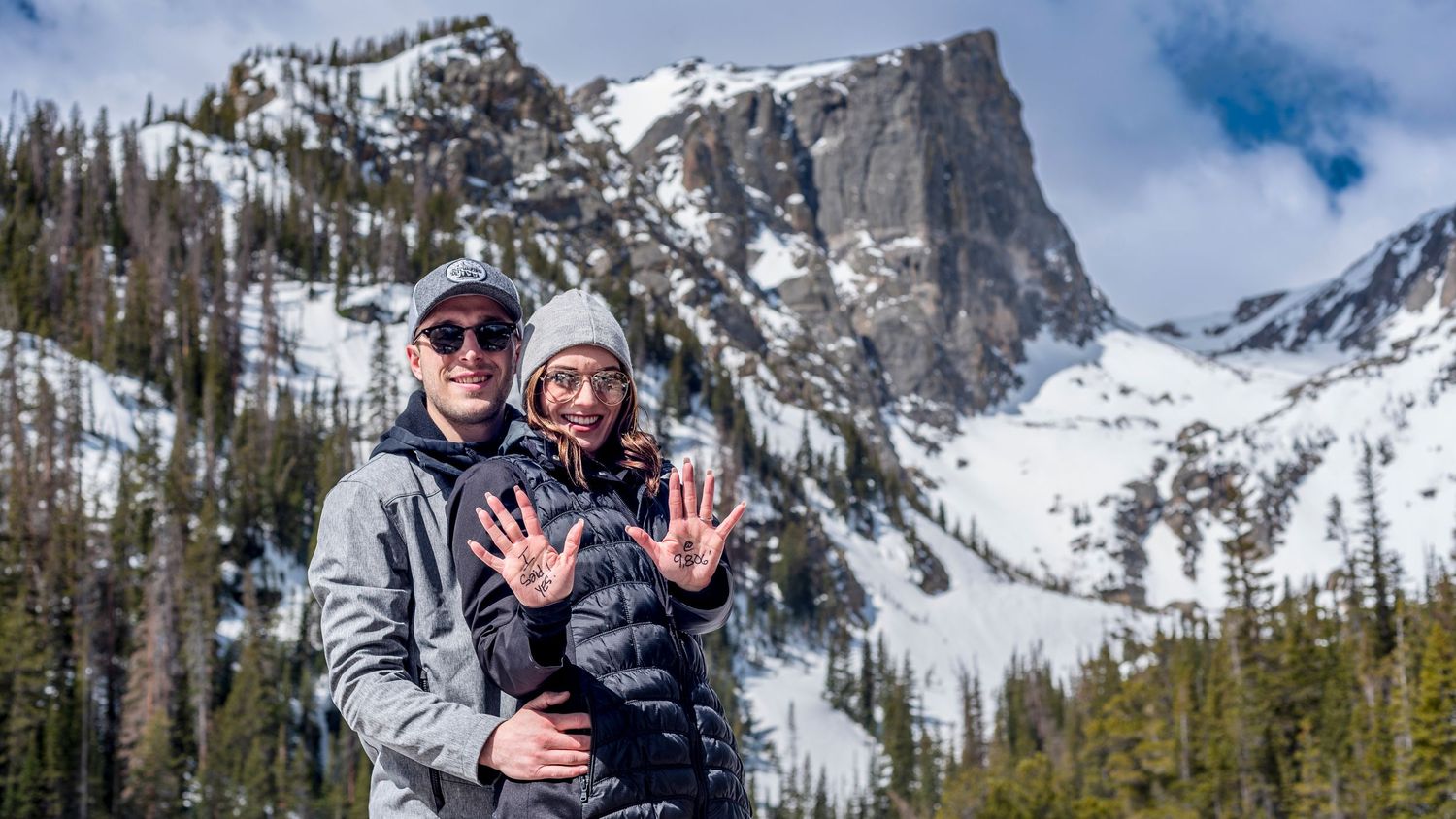 Newly engaged couple showing off her I SAID YES hand after her surprised her with a marriage proposal inside RMNP at Dream Lake.