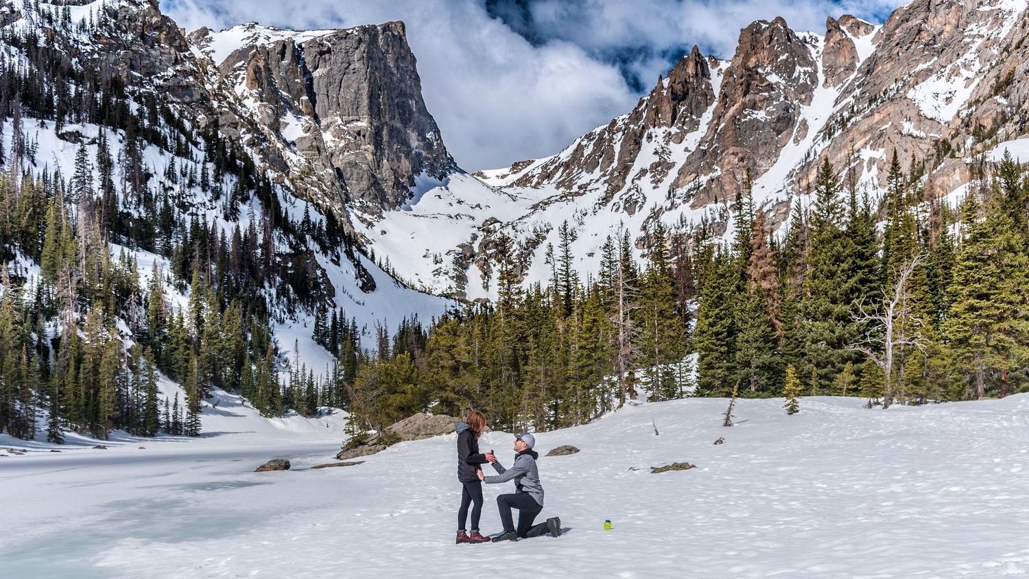 Man popping the question at Dream Lake in Rocky Mountain National Park for a surprise marriage proposal captured by hidden photographer