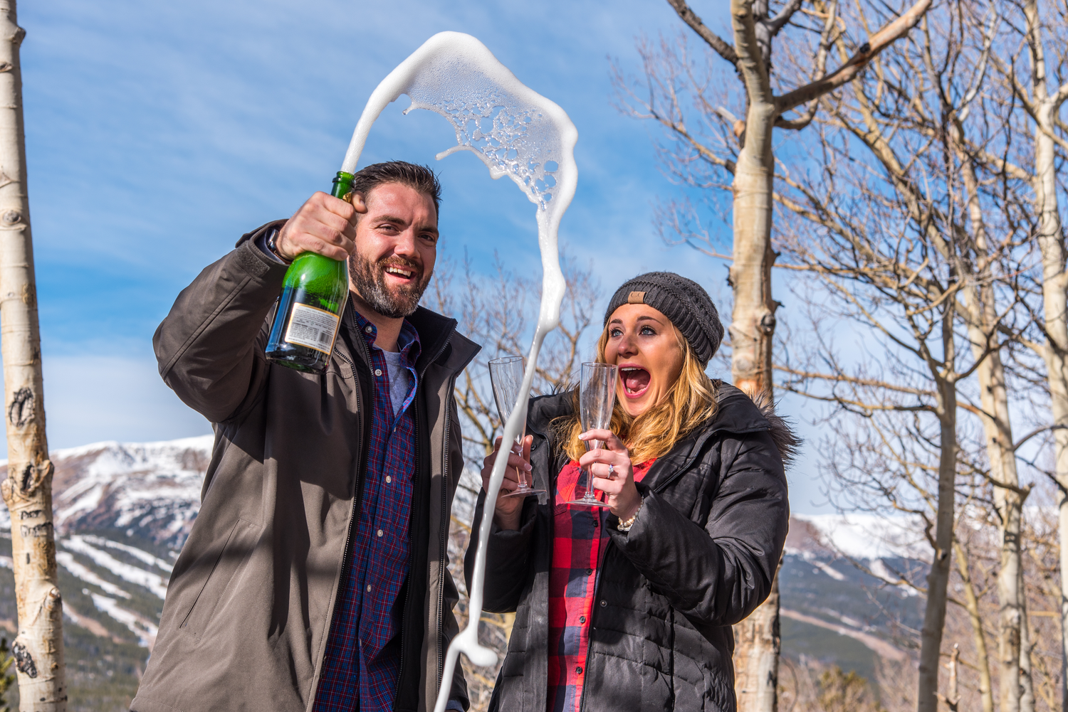 Popping champagne to celebrate their fresh engagement after he asked her to marry him in Breckenridge, CO
