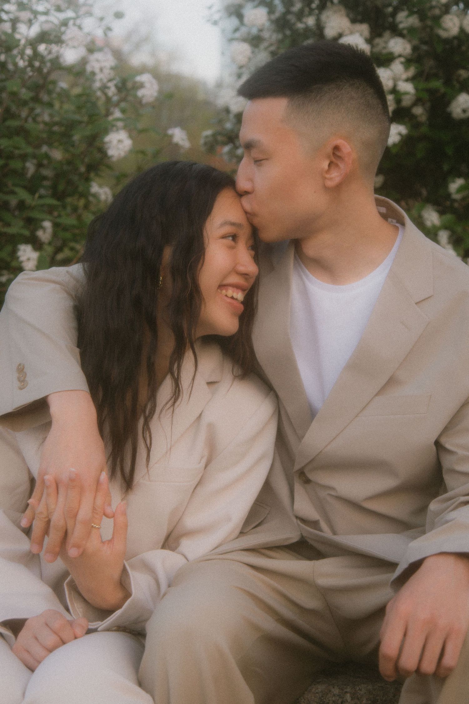 A couple in matching beige outfits shares intimate romantic moments together during an outdoor photoshoot.