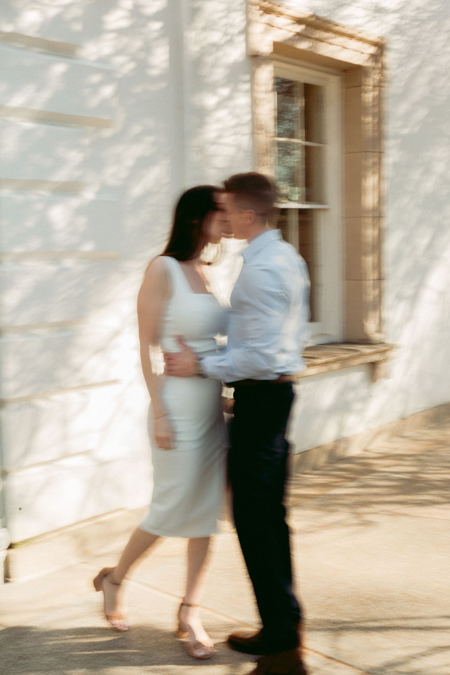 A motion sequence captures two dancers moving together in a bright sunlit room against a white wall.