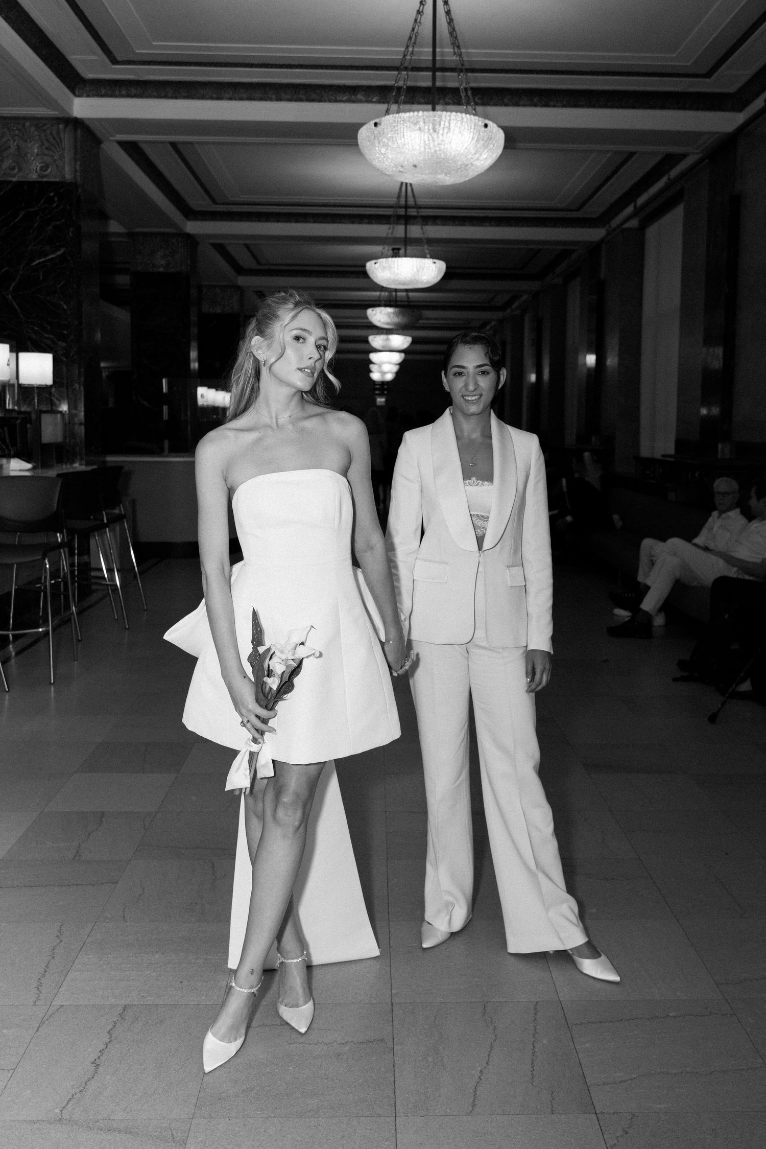 A sequence of black and white photos showing a couple in formal white attire walking through an elegant hallway.