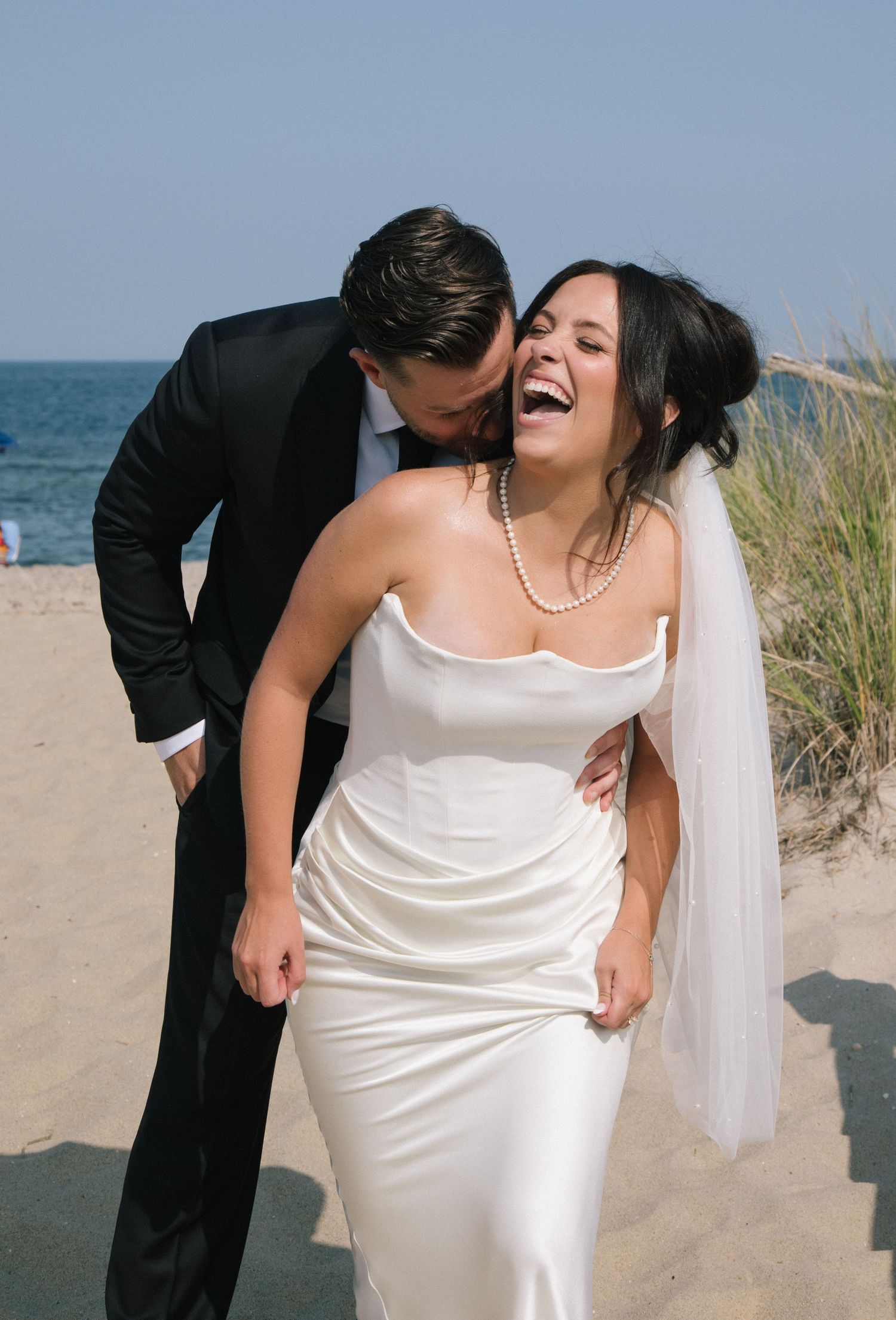 A candid beach wedding moment captured with ocean waves in the background.