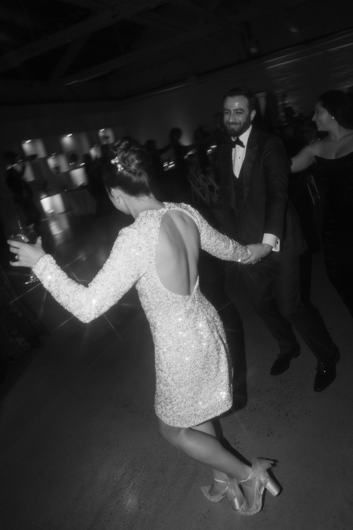 Wedding guests dance energetically on the reception dance floor in formal attire.