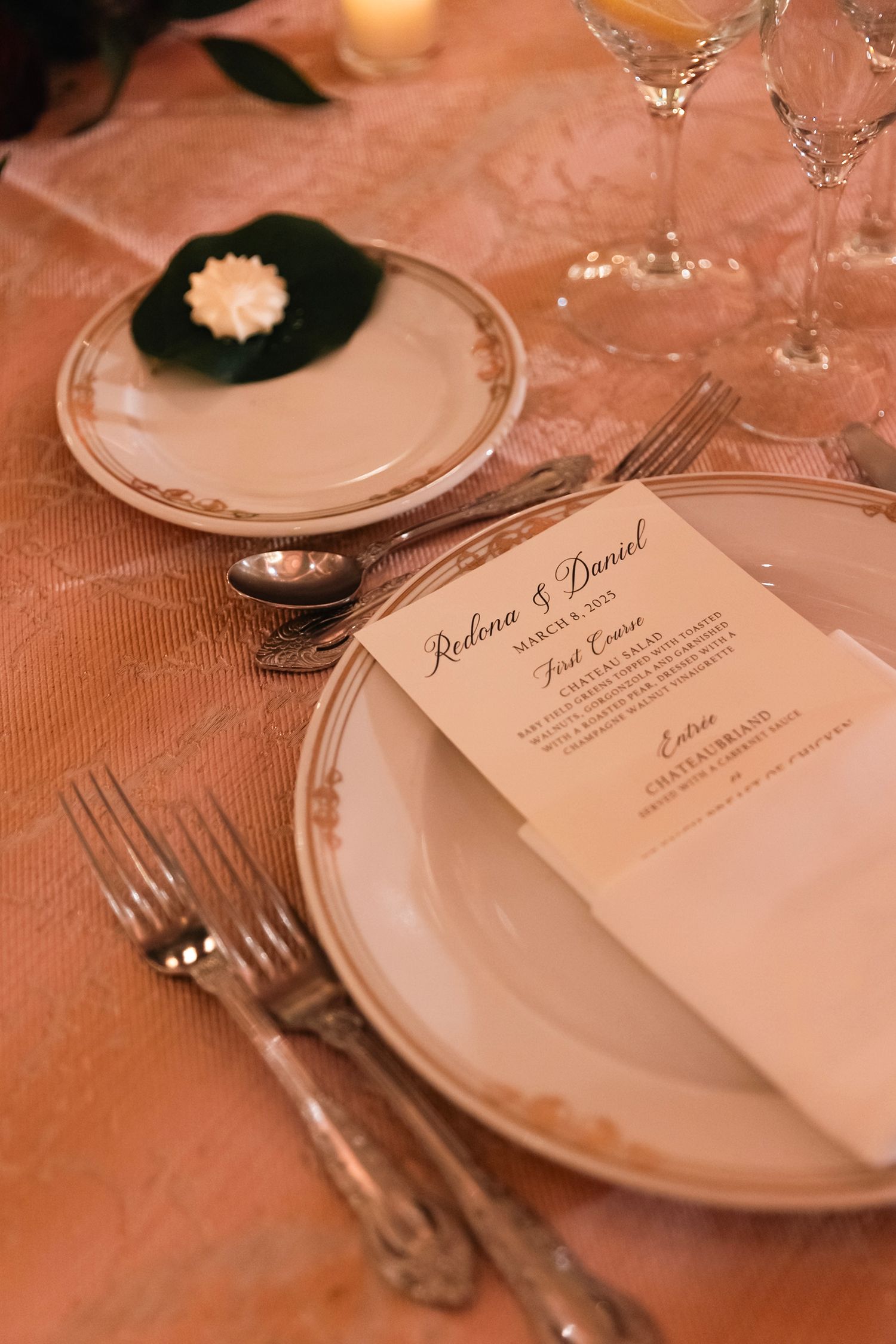 Elegant place settings at a wedding reception with menu cards and fine china plates.