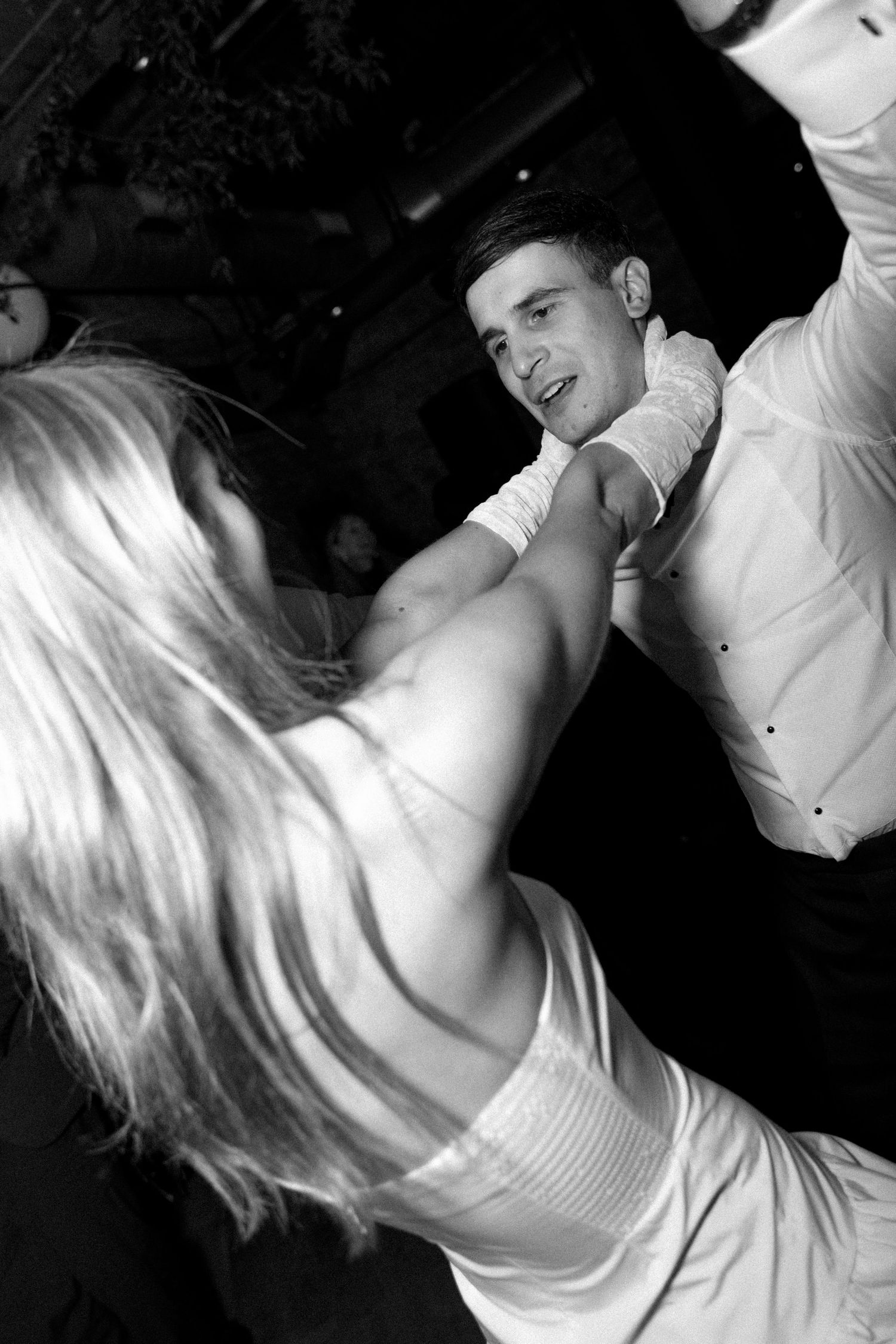 A black and white photo of two people dancing energetically at a nightclub or party.