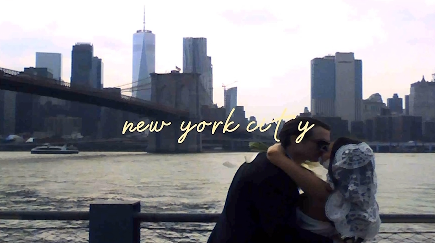 Panoramic view of the New York City downtown skyline with 'New York City' text overlay against a sunset sky.