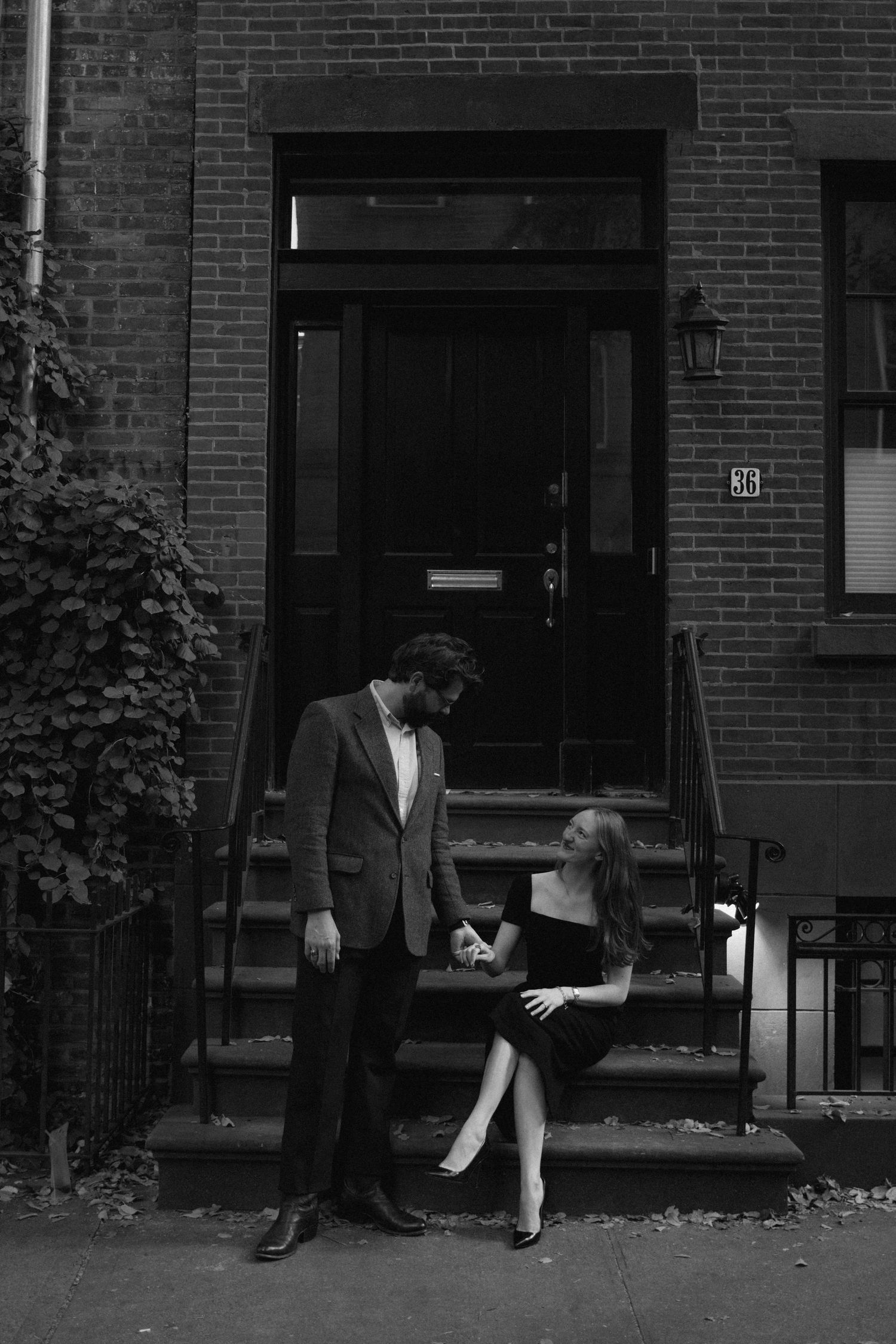 A sequence of black and white photos showing a couple meeting and embracing outside a brick building entrance.