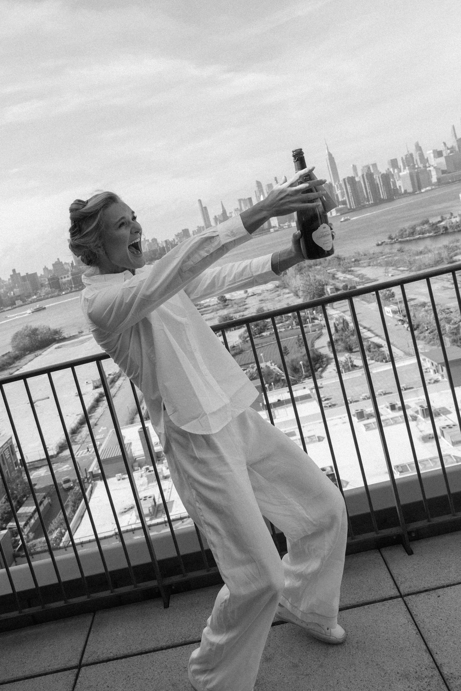 A person in white clothing dances expressively on a rooftop terrace with a city skyline visible in the background.