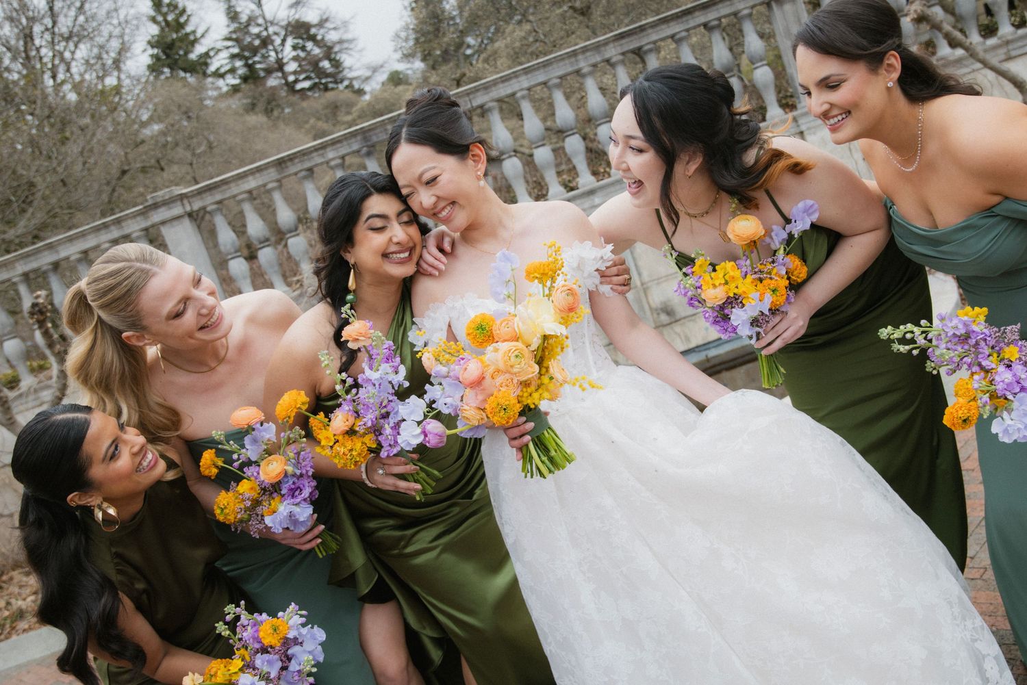 Wedding party with bridesmaids in olive green dresses holding vibrant bouquets.