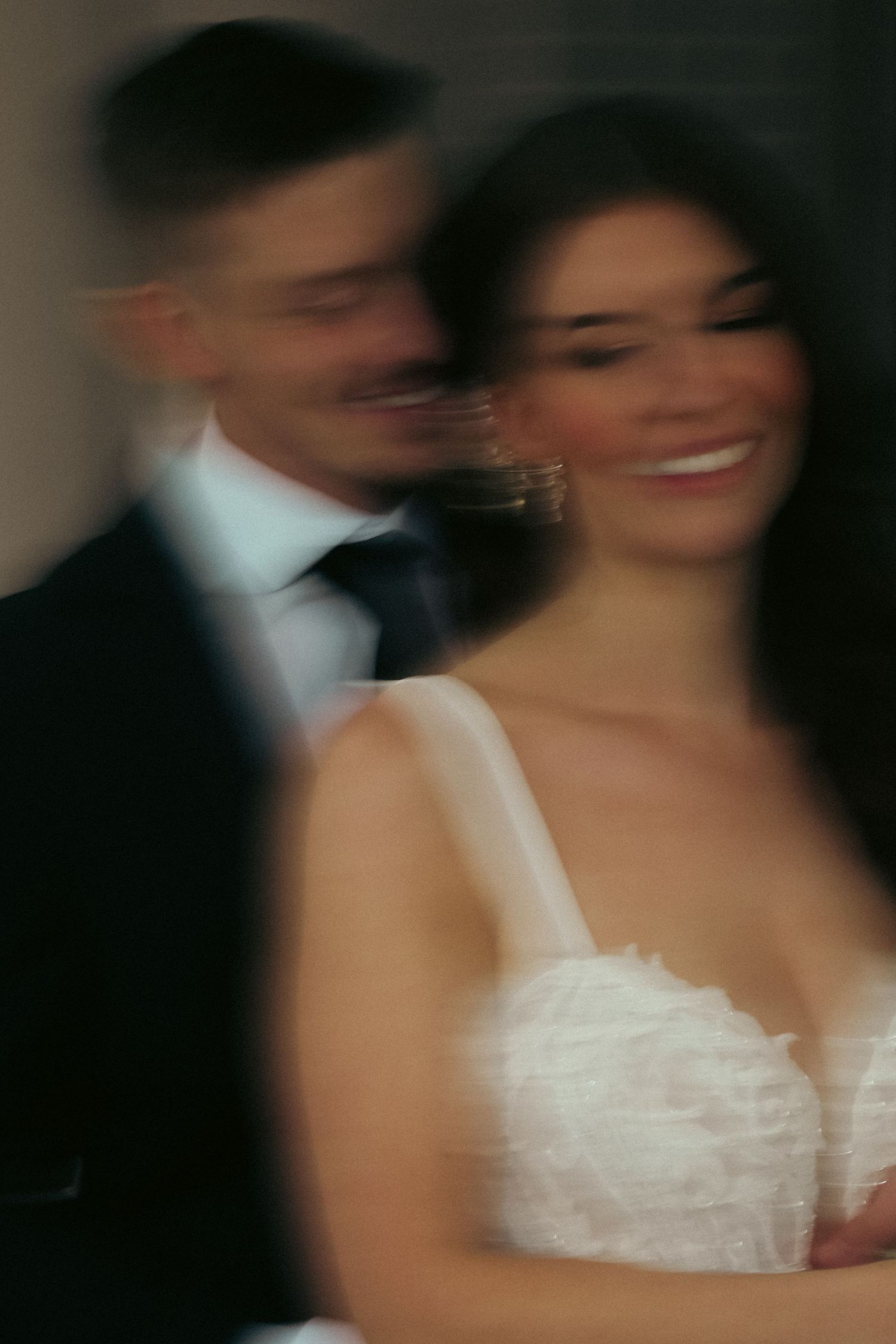 A dreamy motion-blurred portrait of a couple in formal wedding attire sharing an intimate moment.