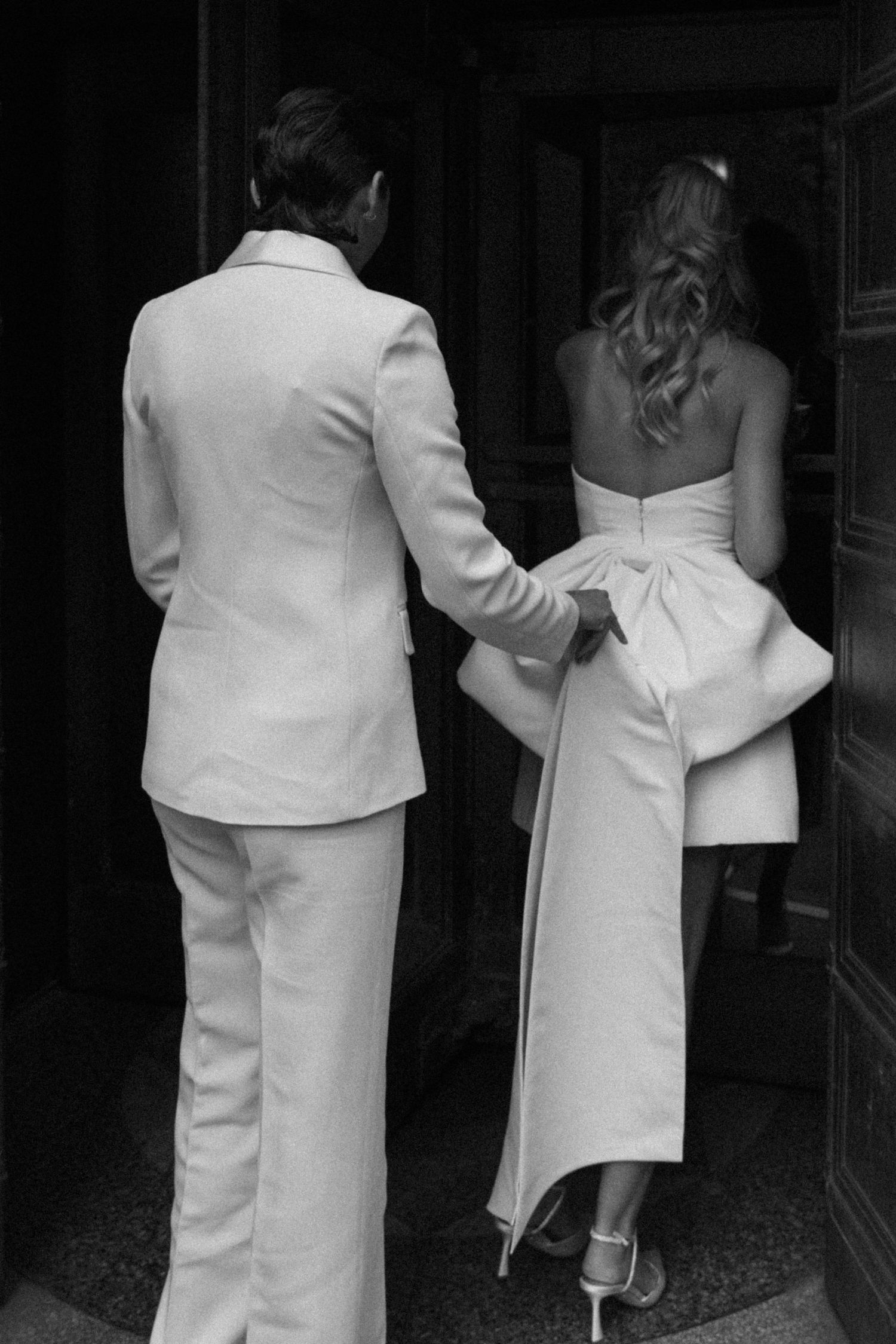 Two figures in white medical uniforms walk down a dark hallway in a black and white photograph.