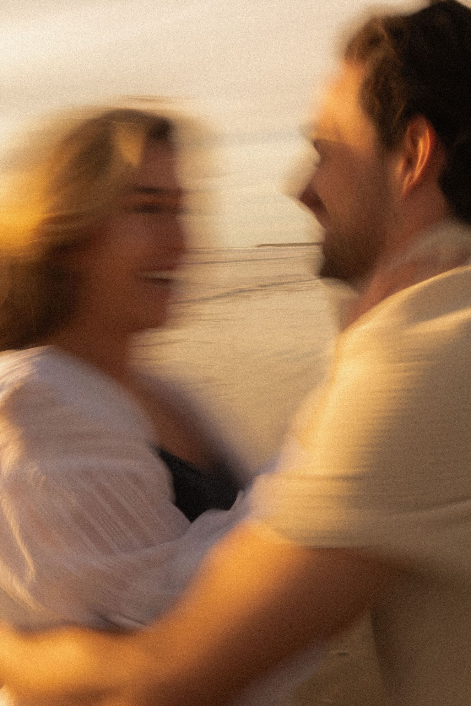 A motion-blurred sequence of two figures dancing together, captured in warm golden lighting during a dance move.
