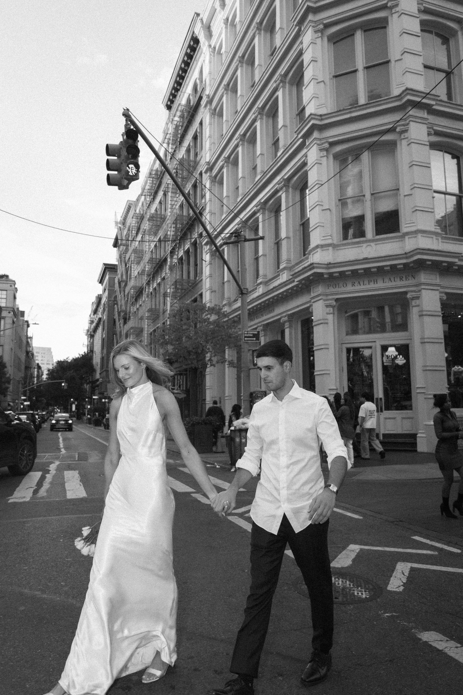 A black and white photo series shows a couple in formal attire walking and posing on a city street corner.