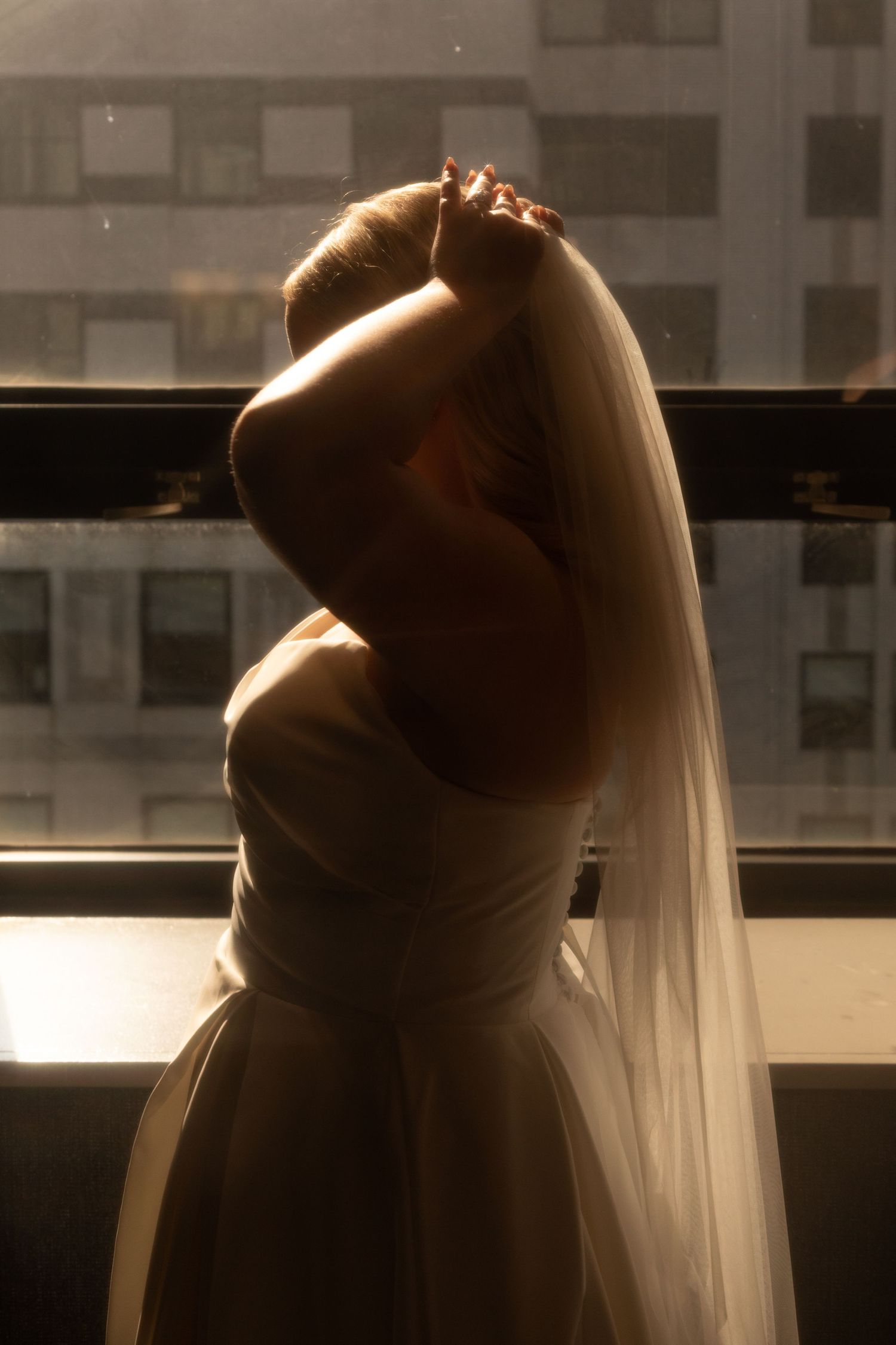 A silhouetted figure in a ballet pose leans gracefully against a barre in dramatic lighting.