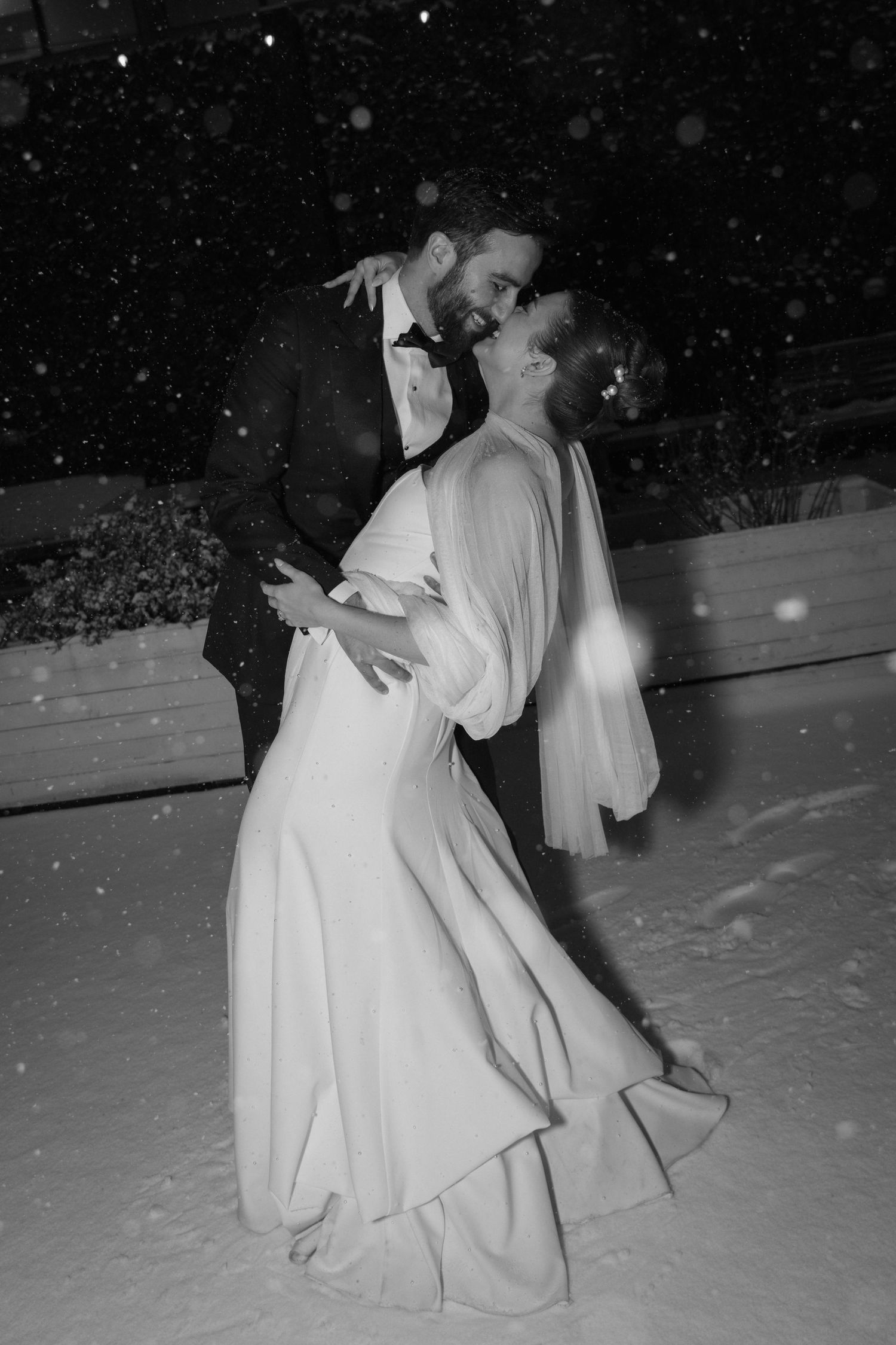 A romantic black and white photo of a couple dancing in the snow on their wedding night.