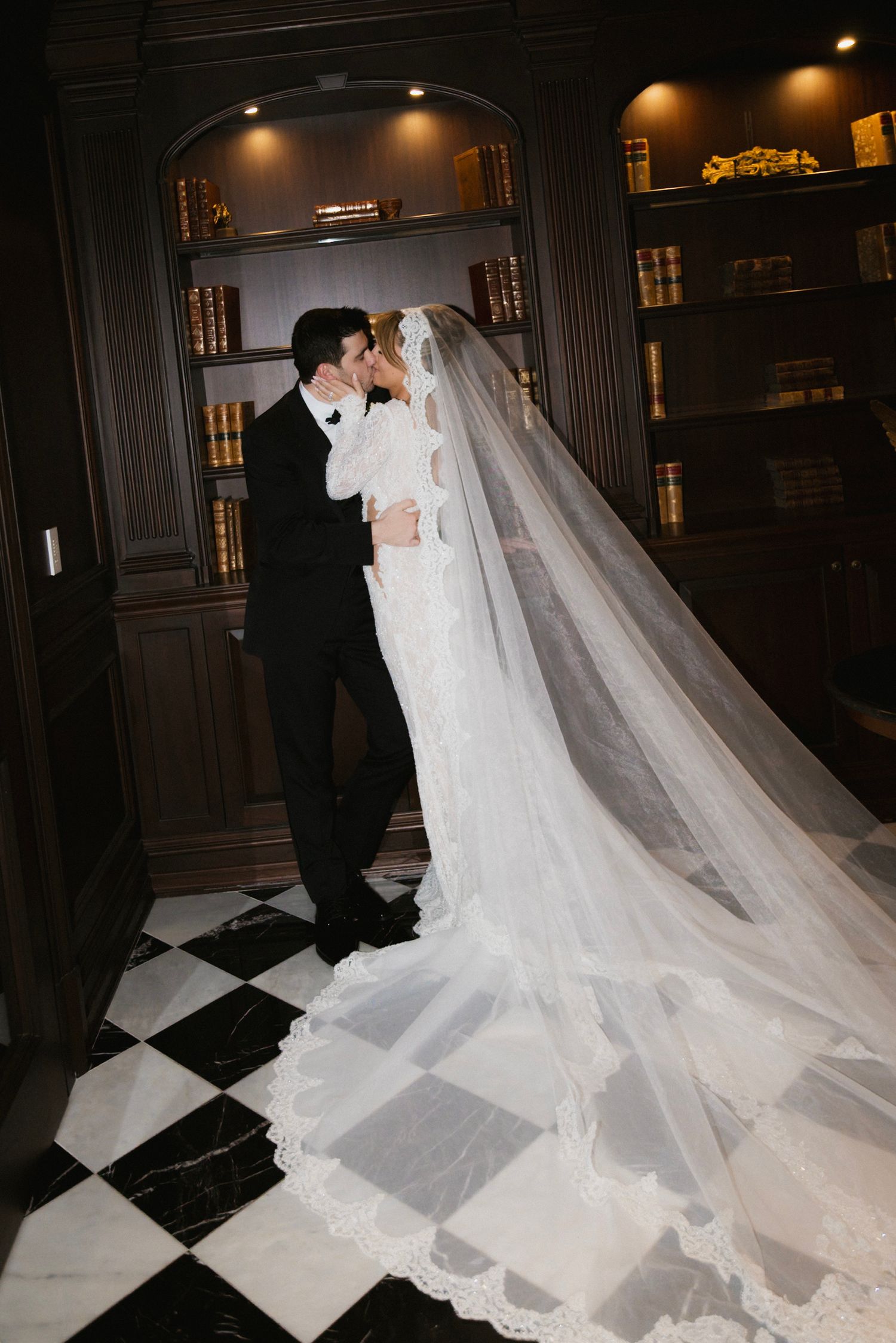 Dramatic wedding portrait on checkered floor with cathedral-length veil.