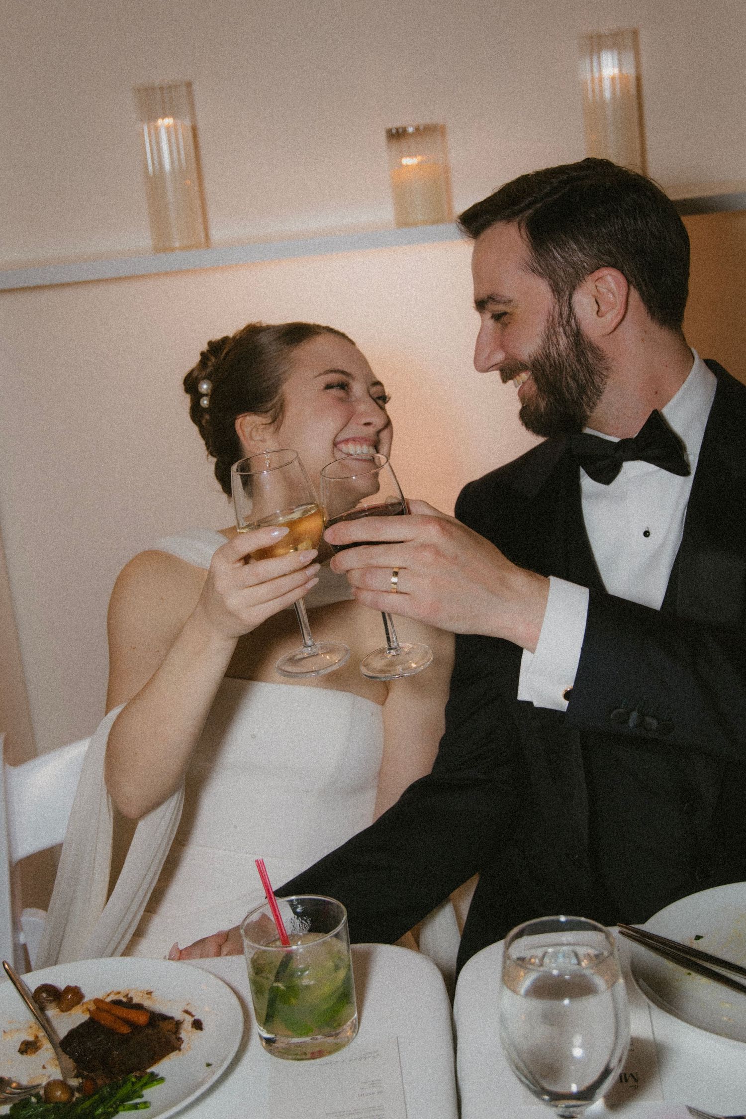 Bride and groom sharing intimate moments over dinner and drinks at their wedding reception.