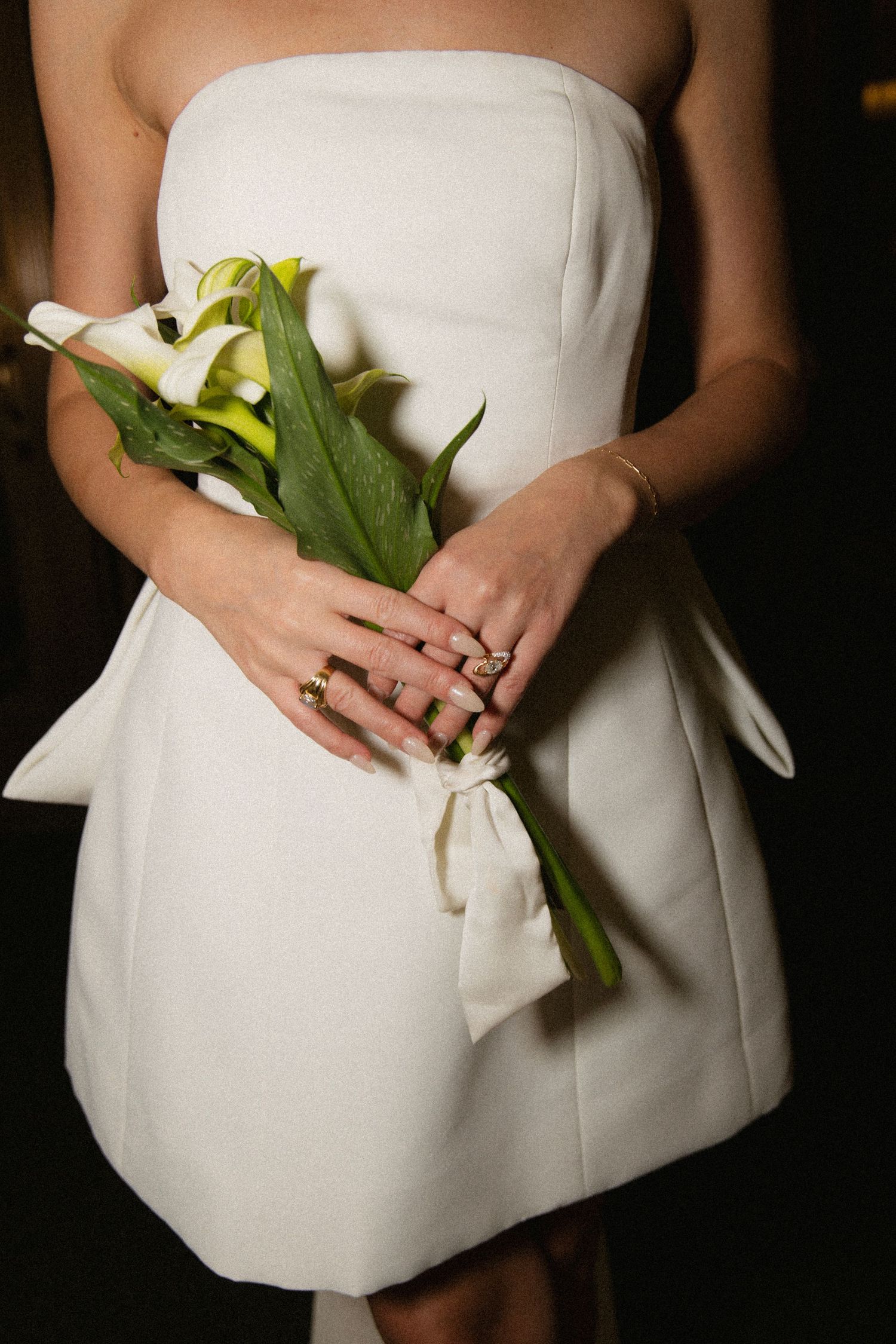 A series of cropped photos showing hands holding white calla lilies against a white bridal dress.