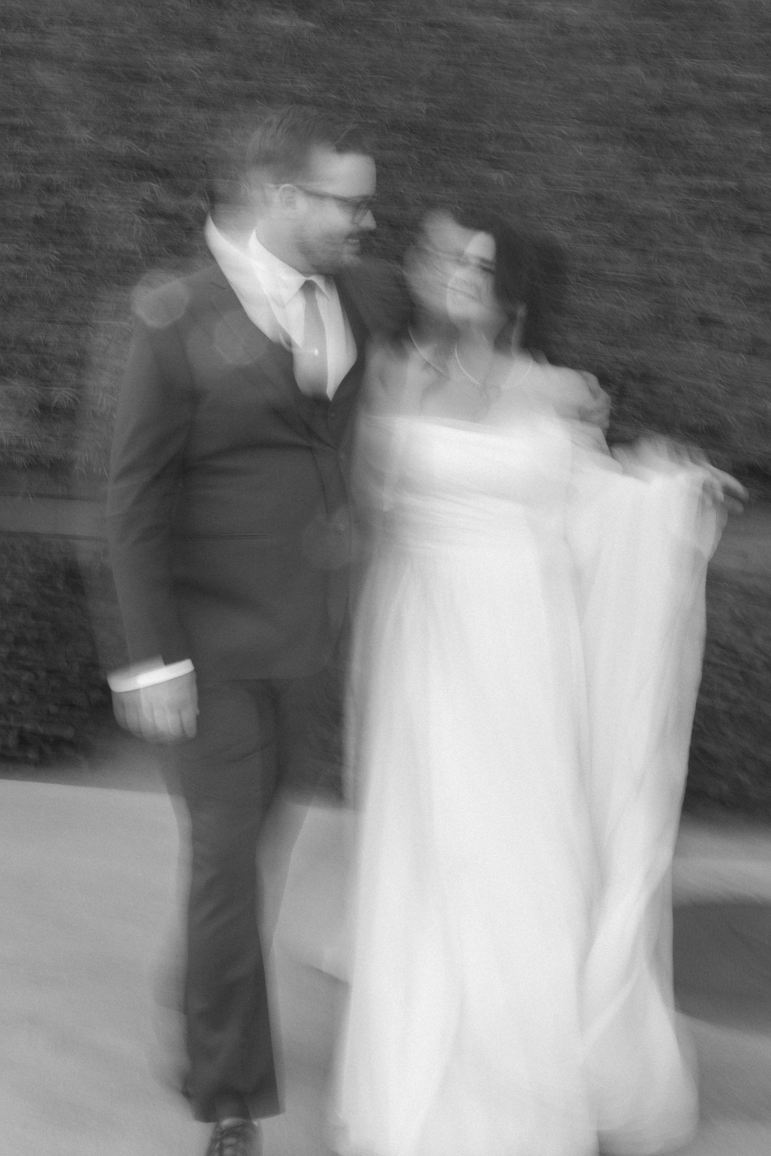 A series of motion-blurred black and white wedding photos showing a couple in formal attire walking together.