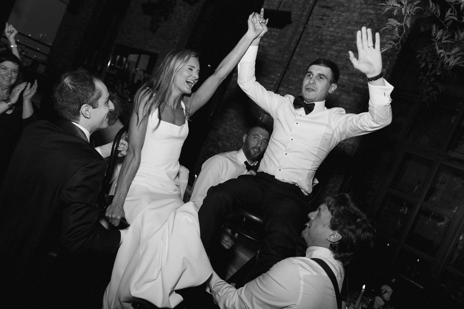 Black and white photos of wedding guests dancing and celebrating with raised arms on the dance floor.