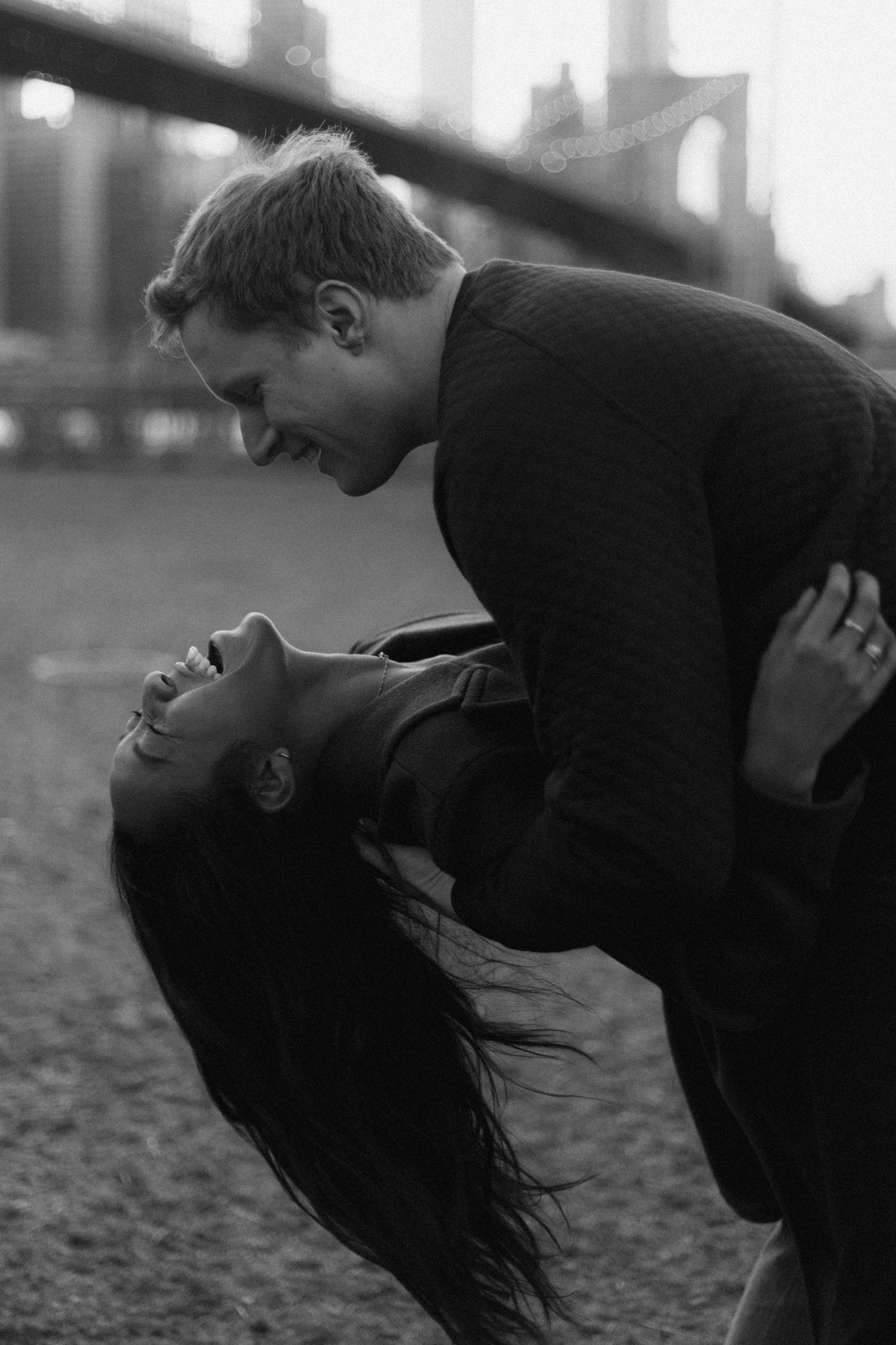 A dramatic black and white photo of a couple in an intimate dance dip pose outdoors.