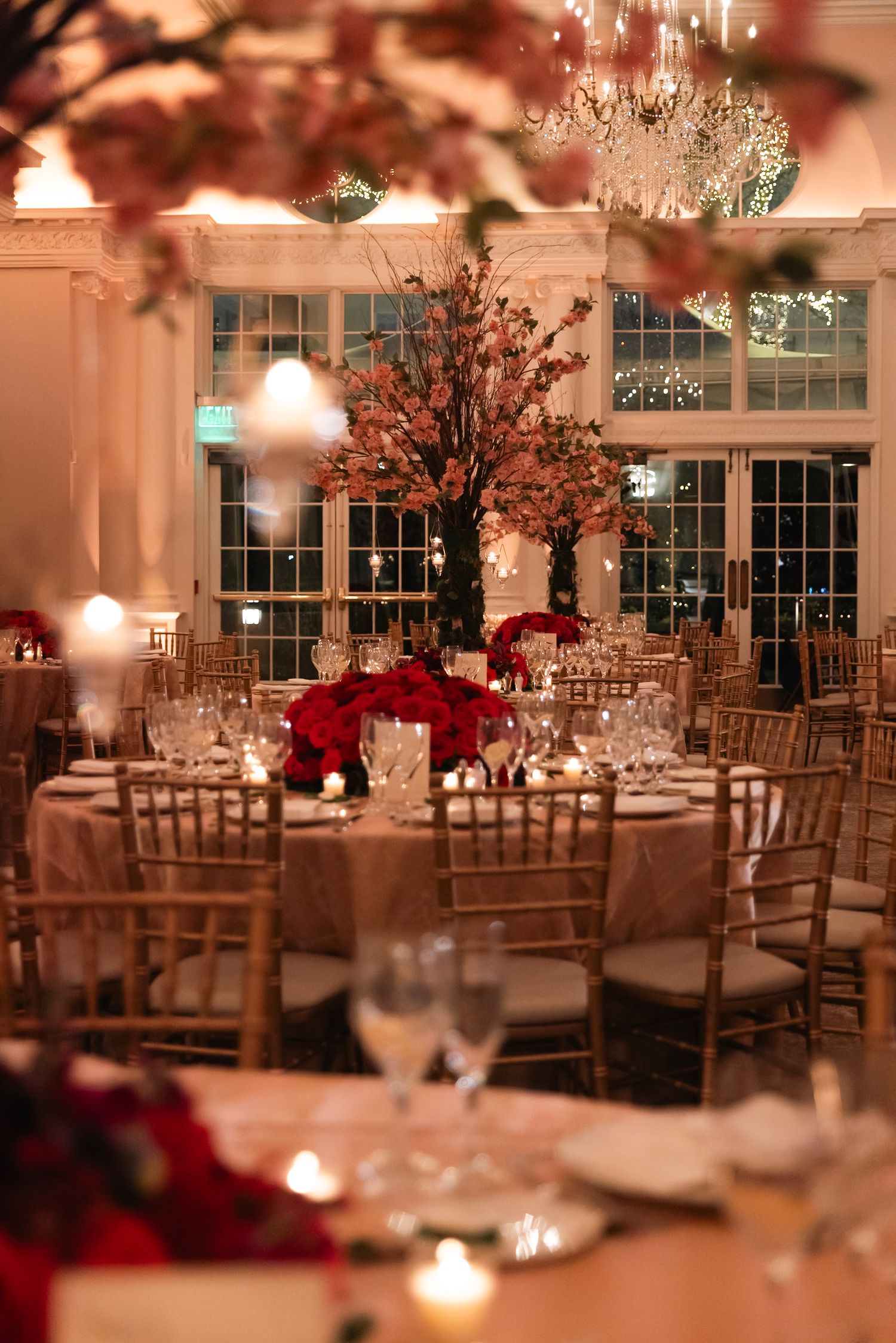 Romantic wedding reception venue with soft lighting, crystal chandeliers and cherry blossom centerpieces.