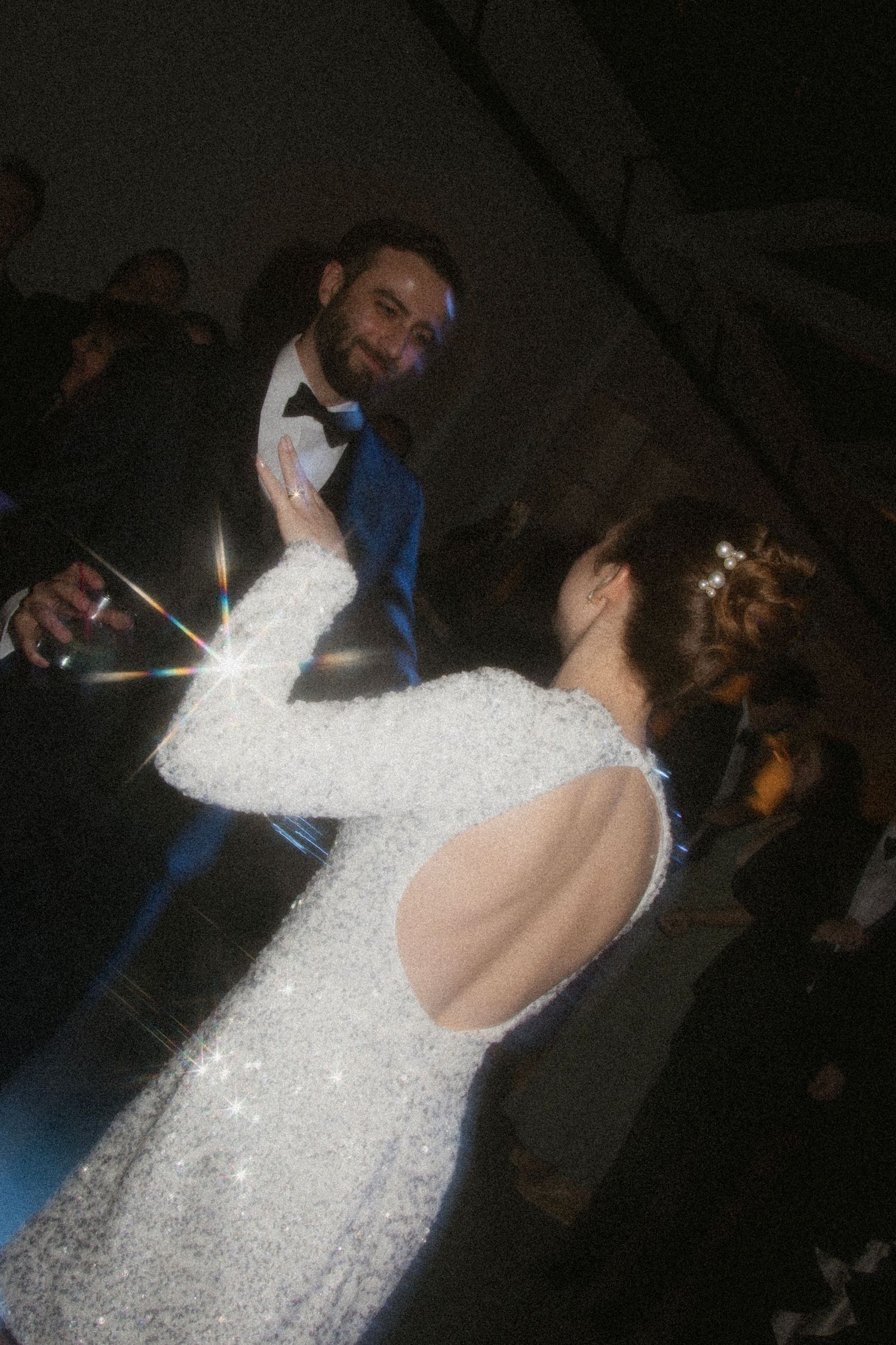 A sparkly wedding dress catches the light as couple dances during their reception.