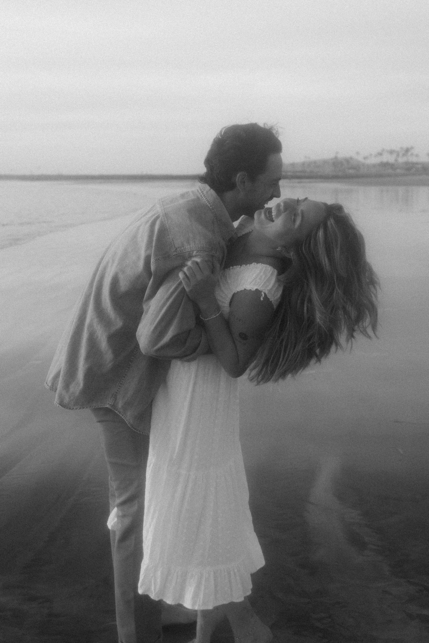 A romantic black and white photo series showing a couple embracing on a misty beach.