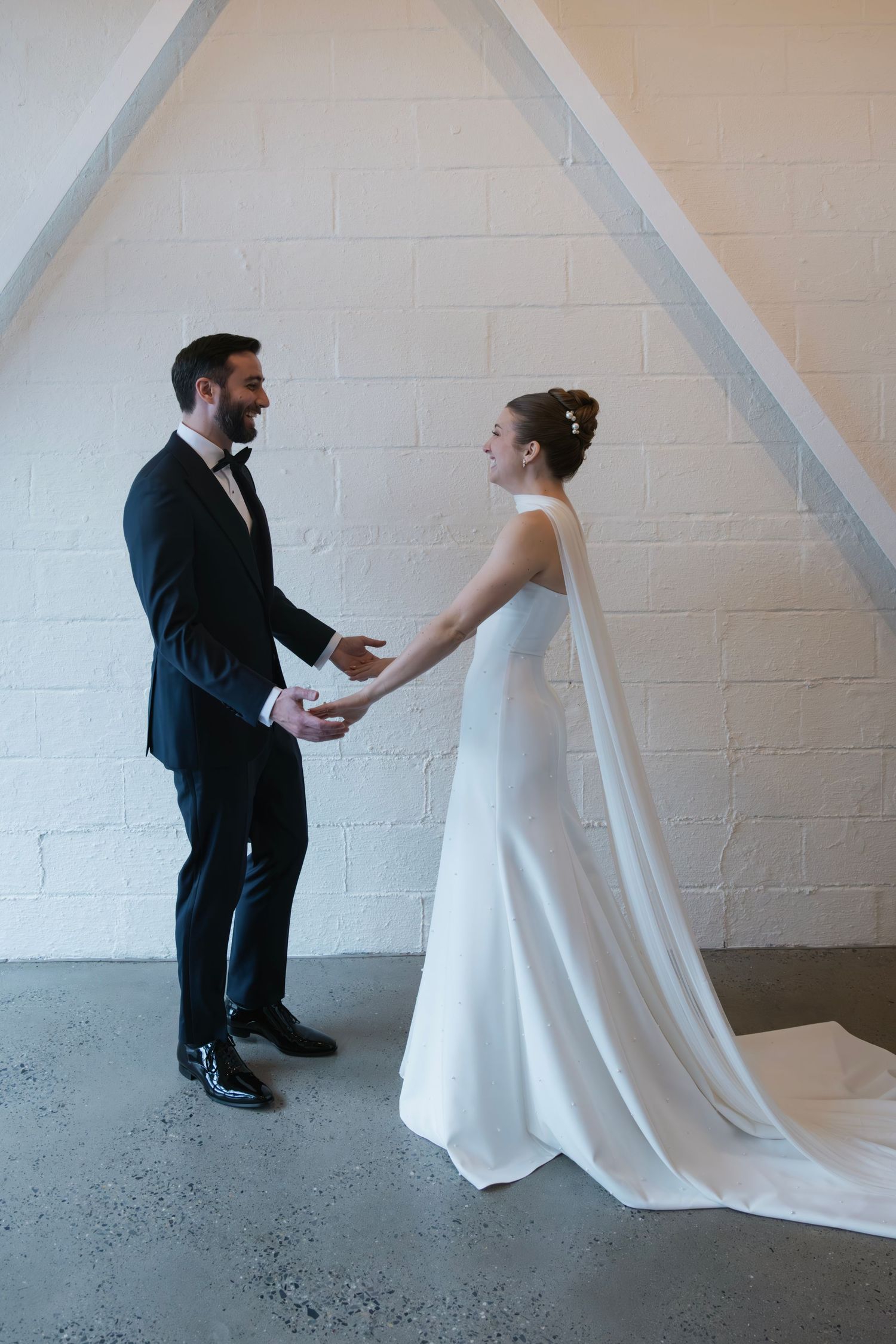 A tender first look between newlyweds in an intimate indoor setting with white brick walls.