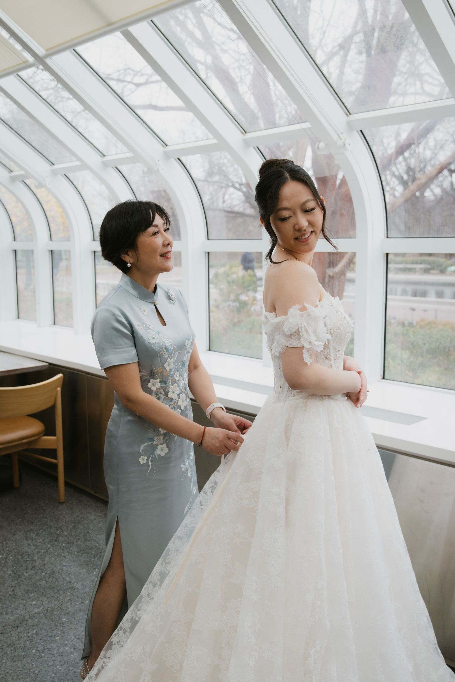 Wedding dress fitting session showing final adjustments and preparations in a bright sunlit room.