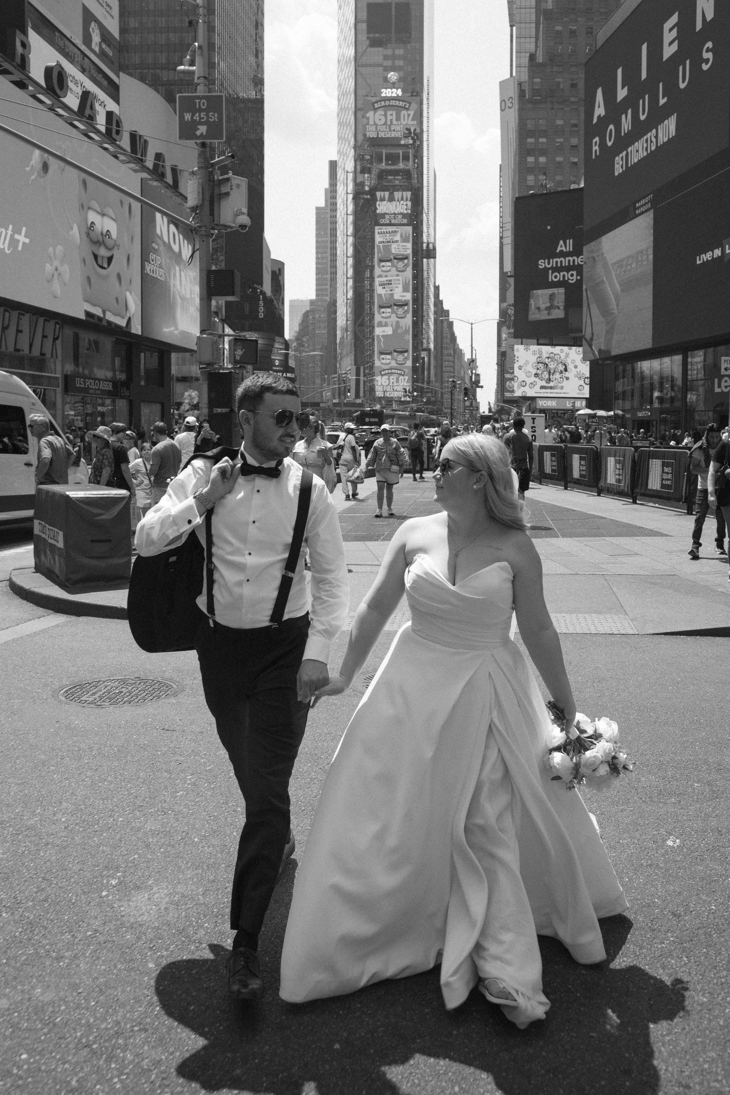 A series of four black and white photos showing a couple in wedding attire walking through Times Square in New York City.