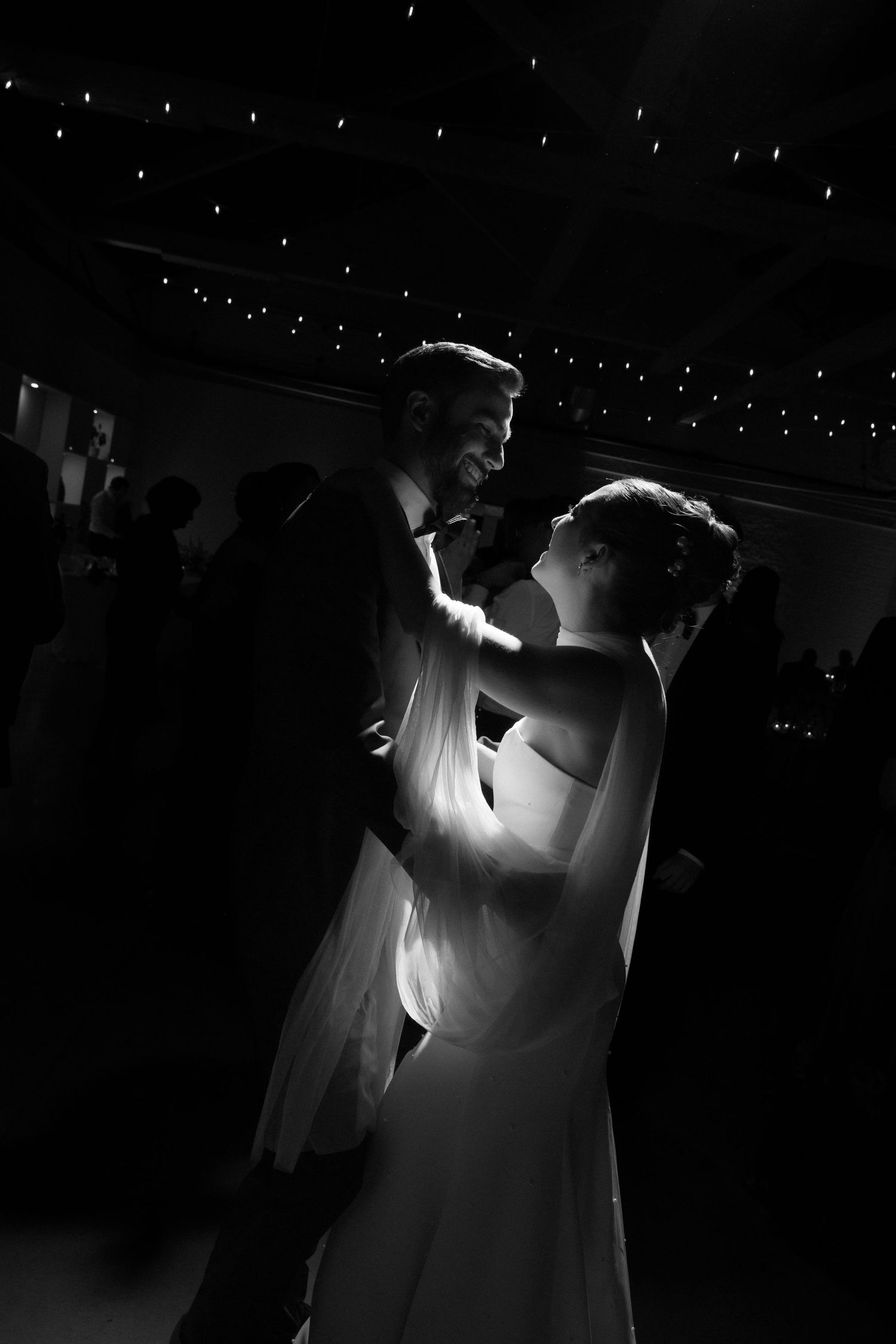 A dramatic black and white shot of a couple dancing at their wedding reception.