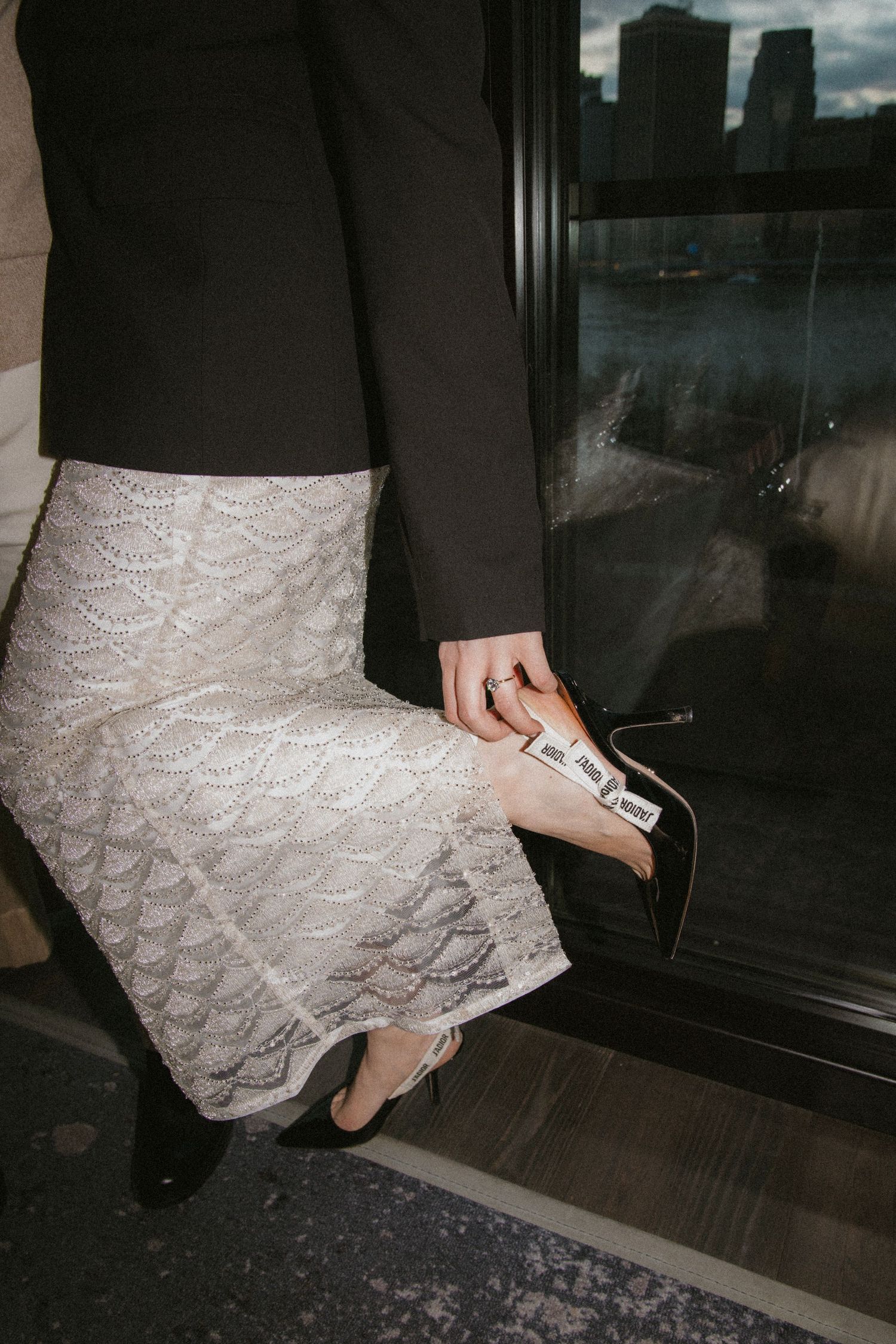 Person wearing a black top and white lace skirt enters doorway in moody lighting conditions.