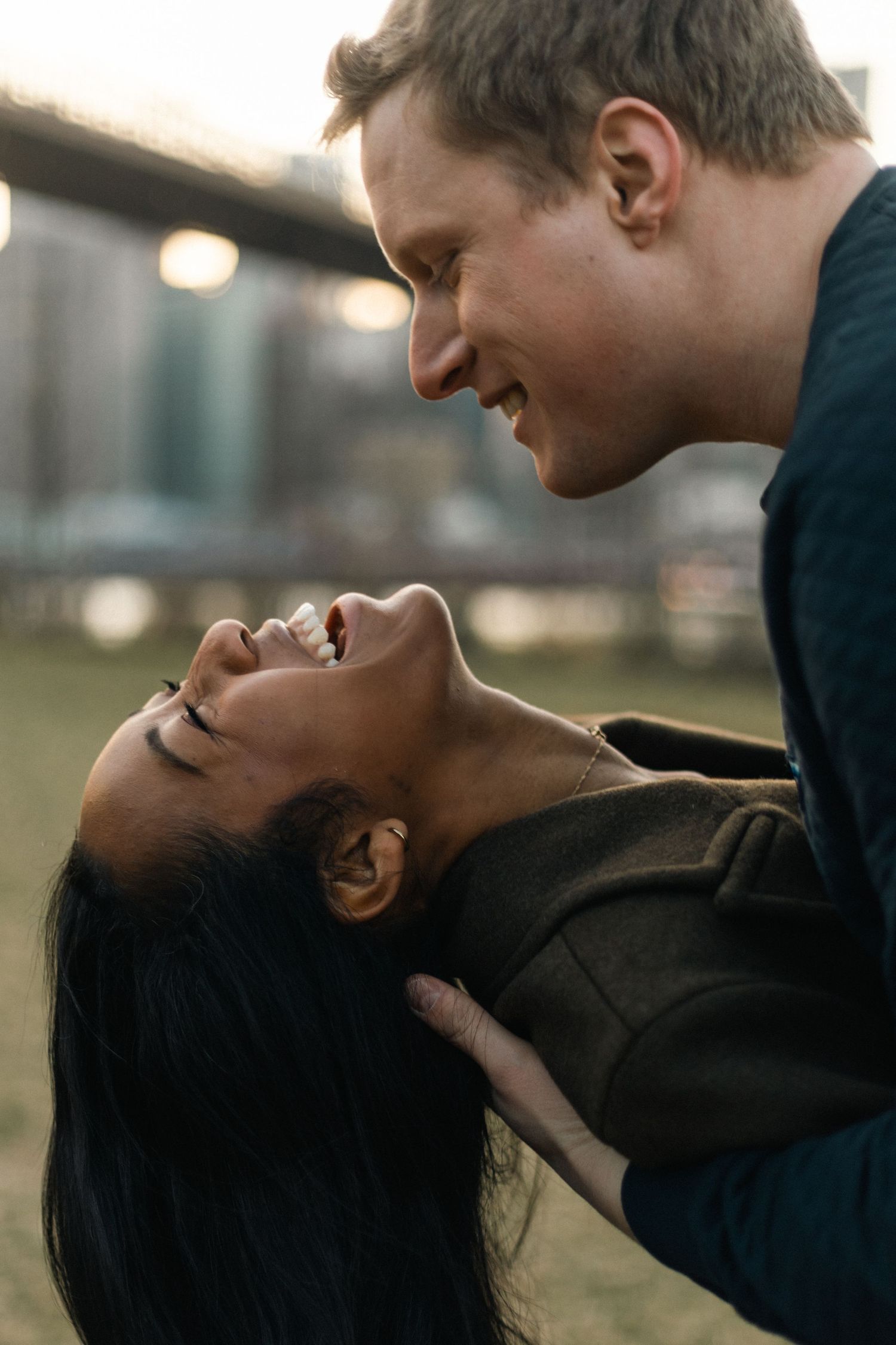 Close-up side profile of two people sharing an intimate loving moment outdoors during golden hour.