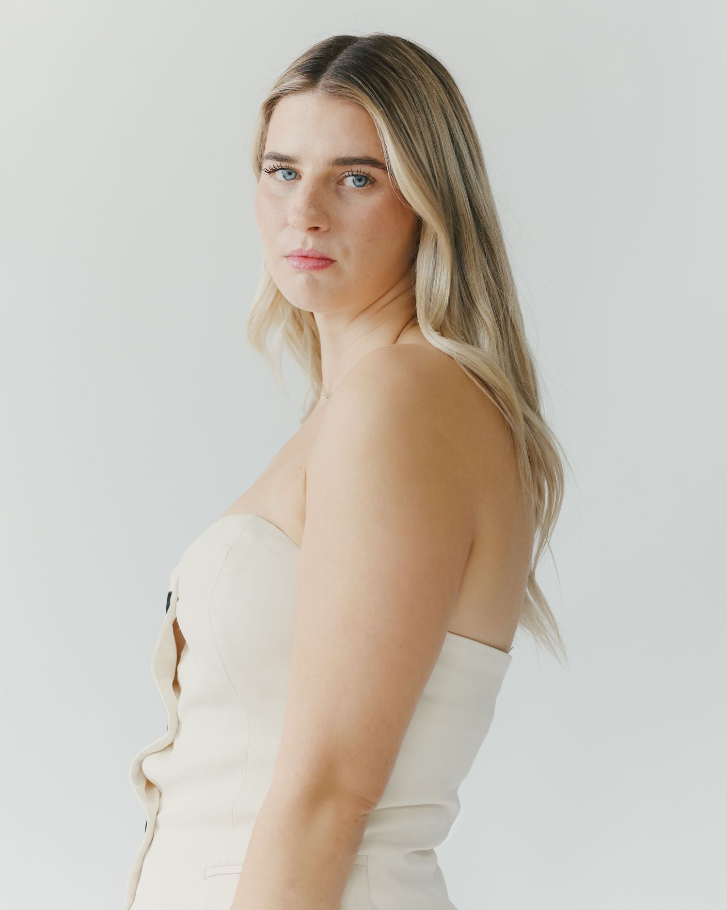 Portrait session with person in cream colored outfit against white background.