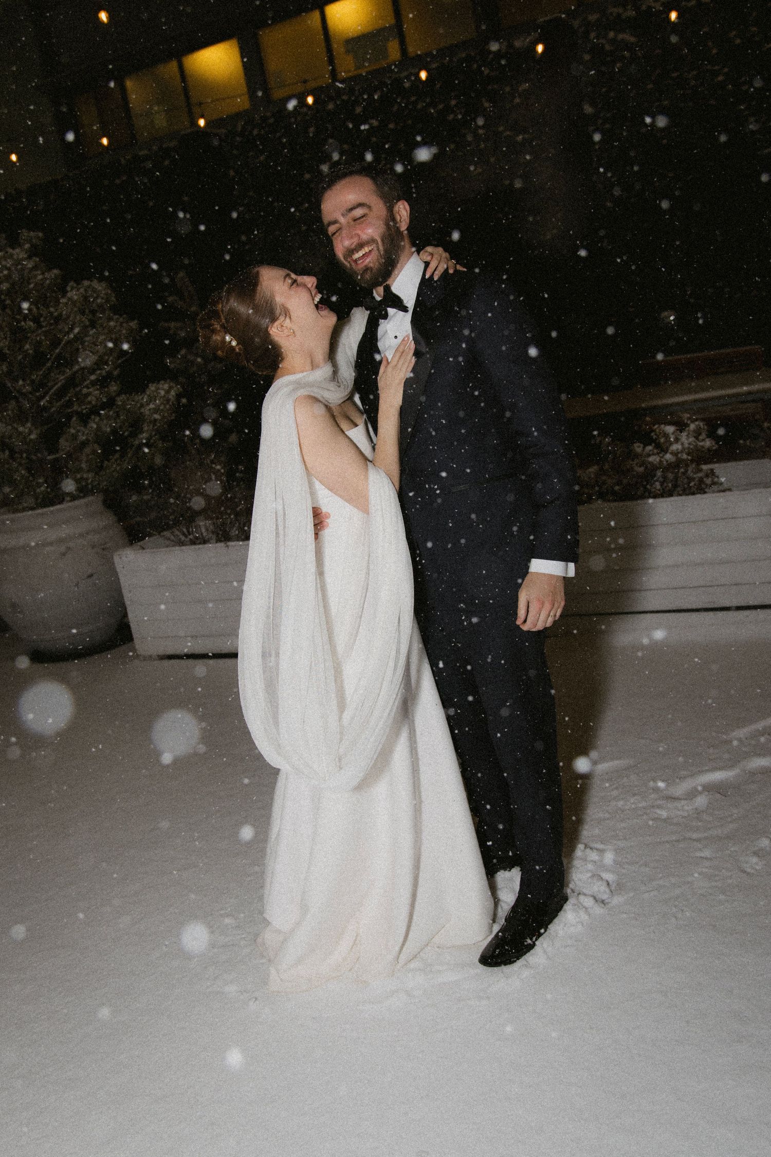 A romantic winter wedding photo with snow falling around a couple on their special night.