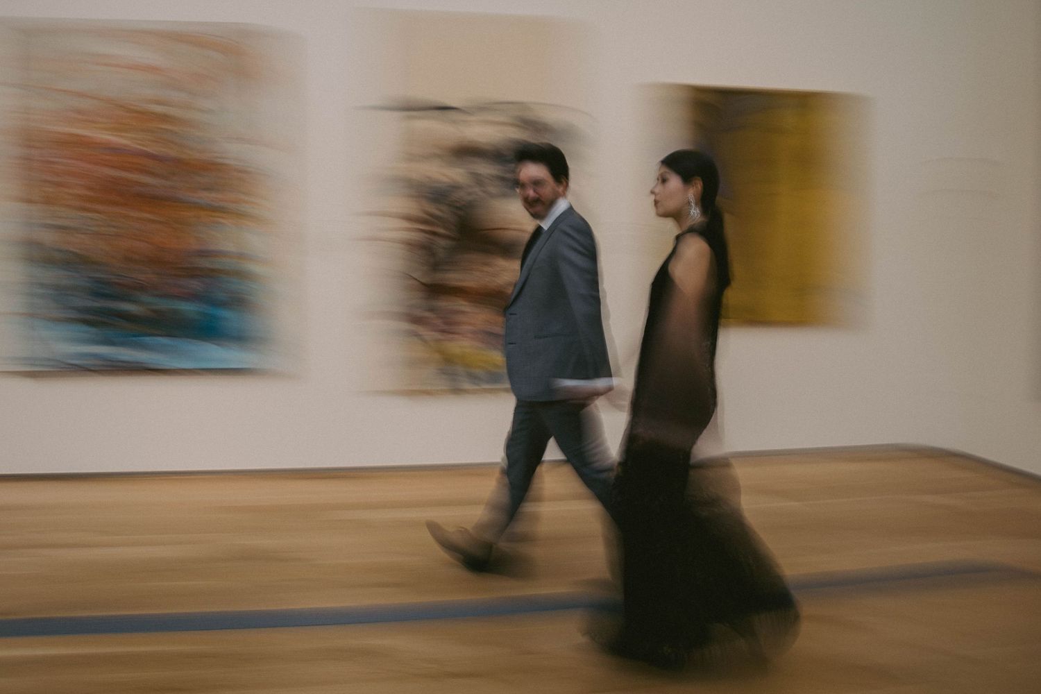 Motion blur photograph of people walking through an art gallery exhibition space.